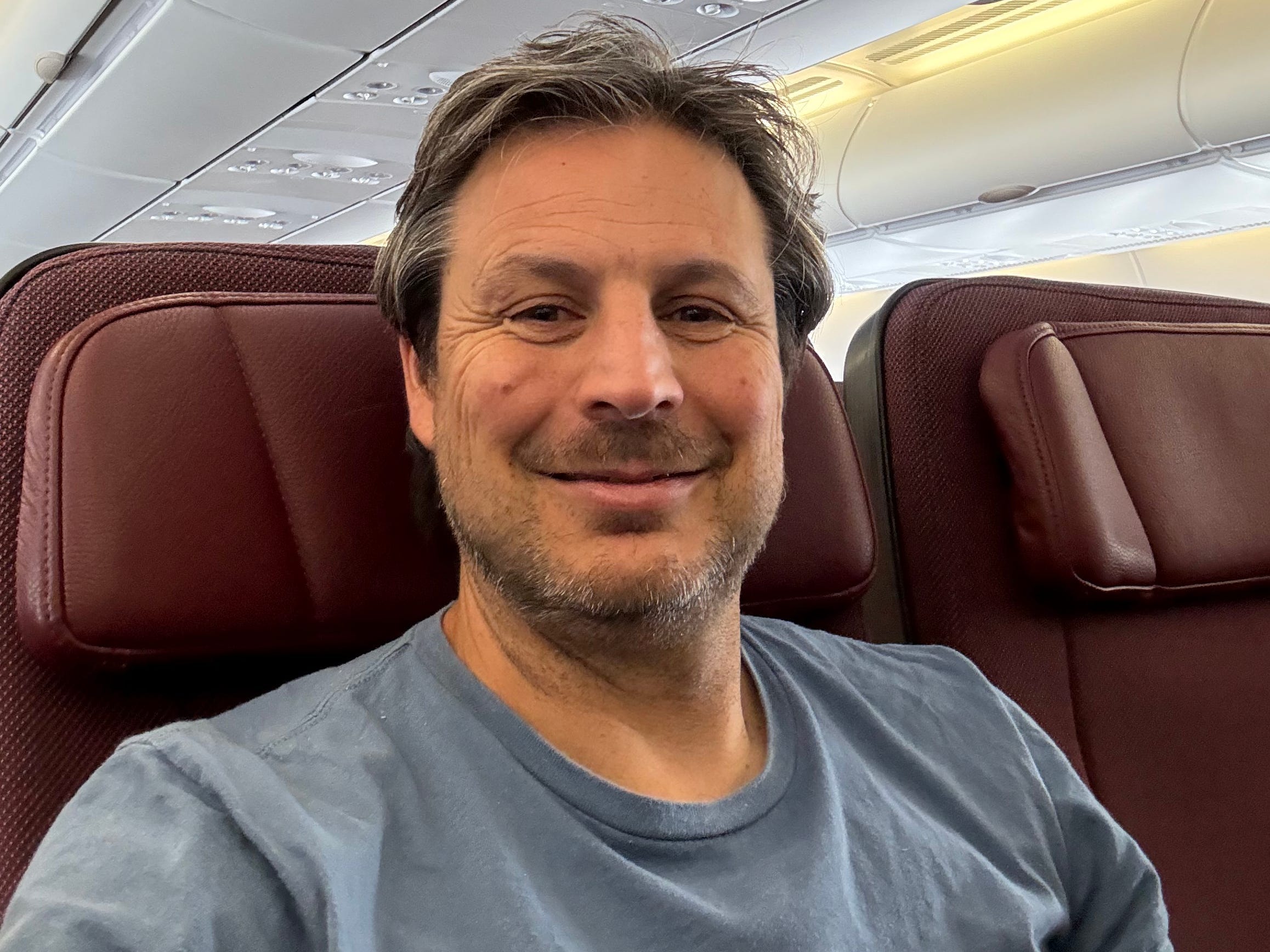 Ash smiles in an airplane seat.