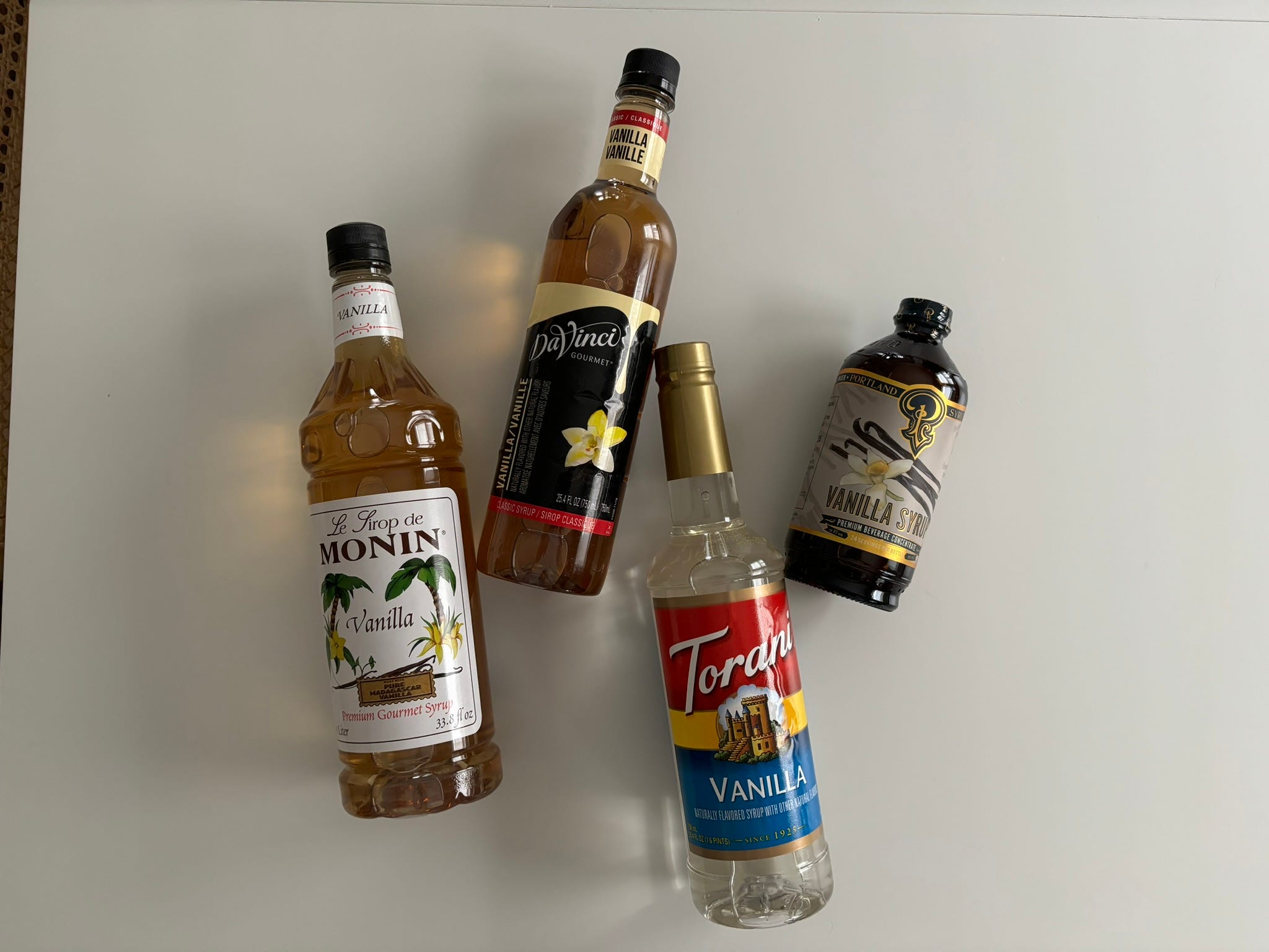 Four different vanilla coffee syrups lying on a countertop