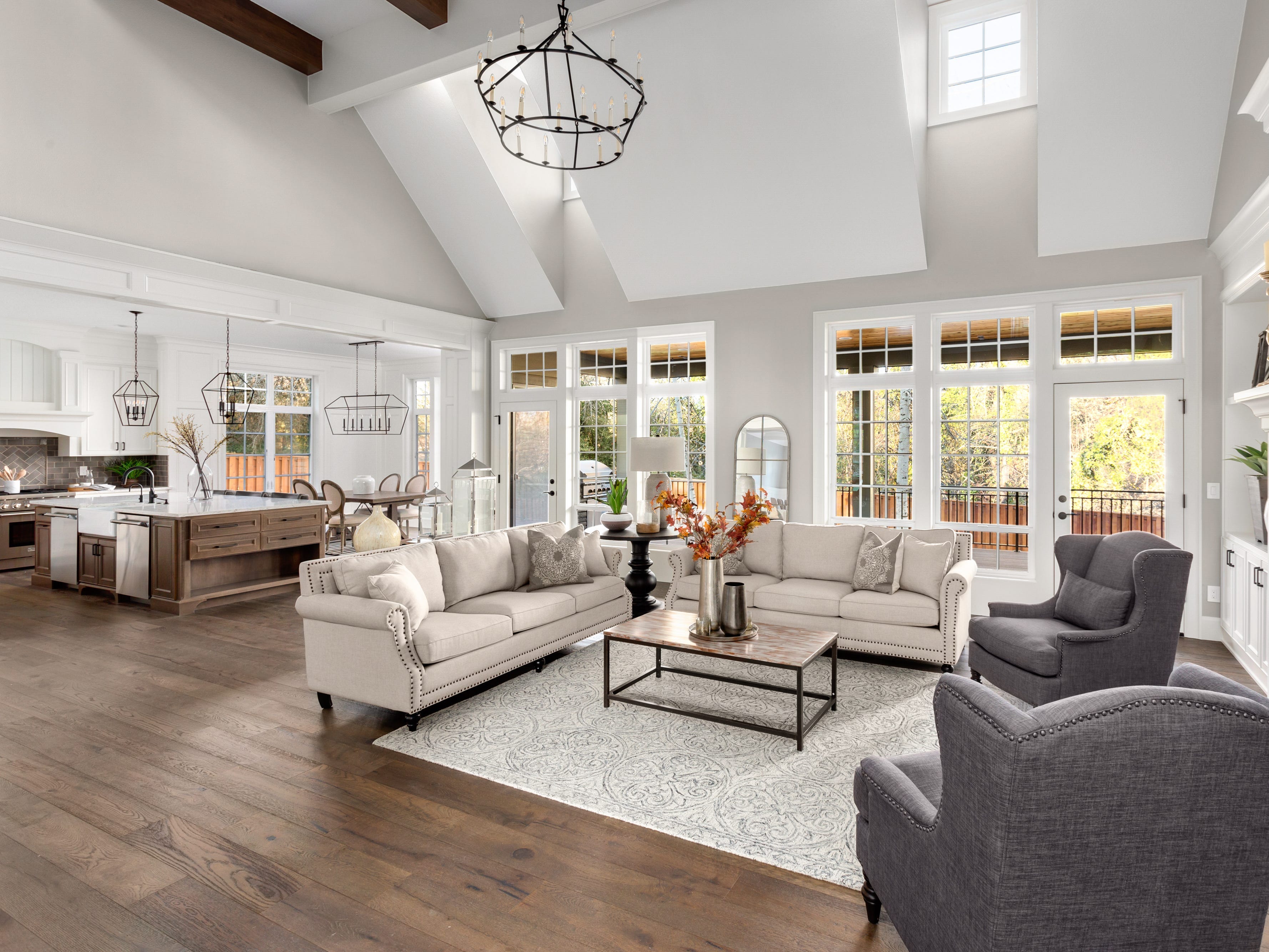 Open-concept living room with tall ceilings and wood floors and white and gray furniture
