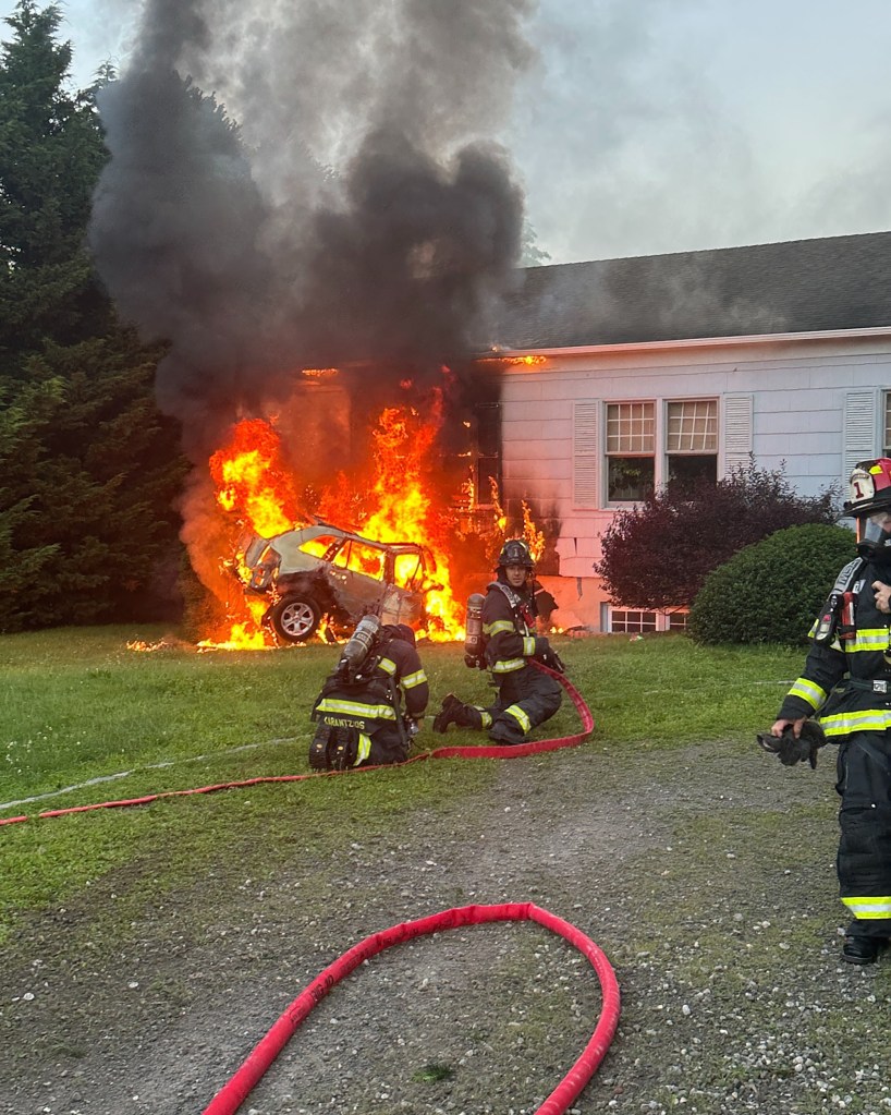 Firefighters battling a car fire that spread to a nearby building.