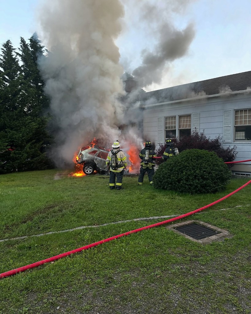 Firefighters battling a car fire that spread to a building.