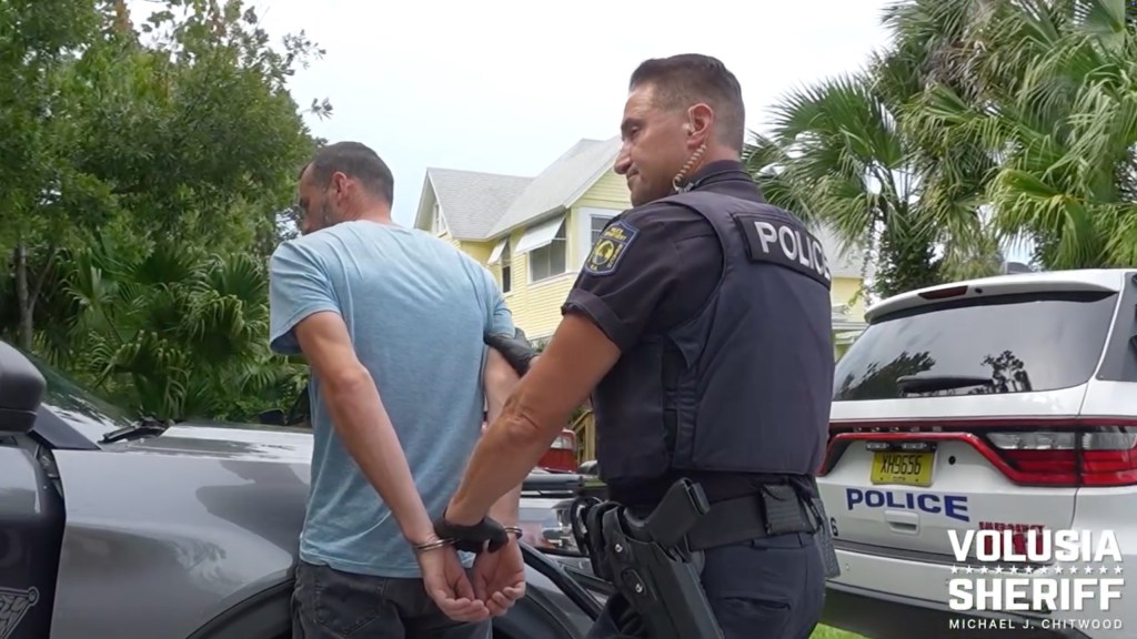 A man in handcuffs being arrested by a police officer.
