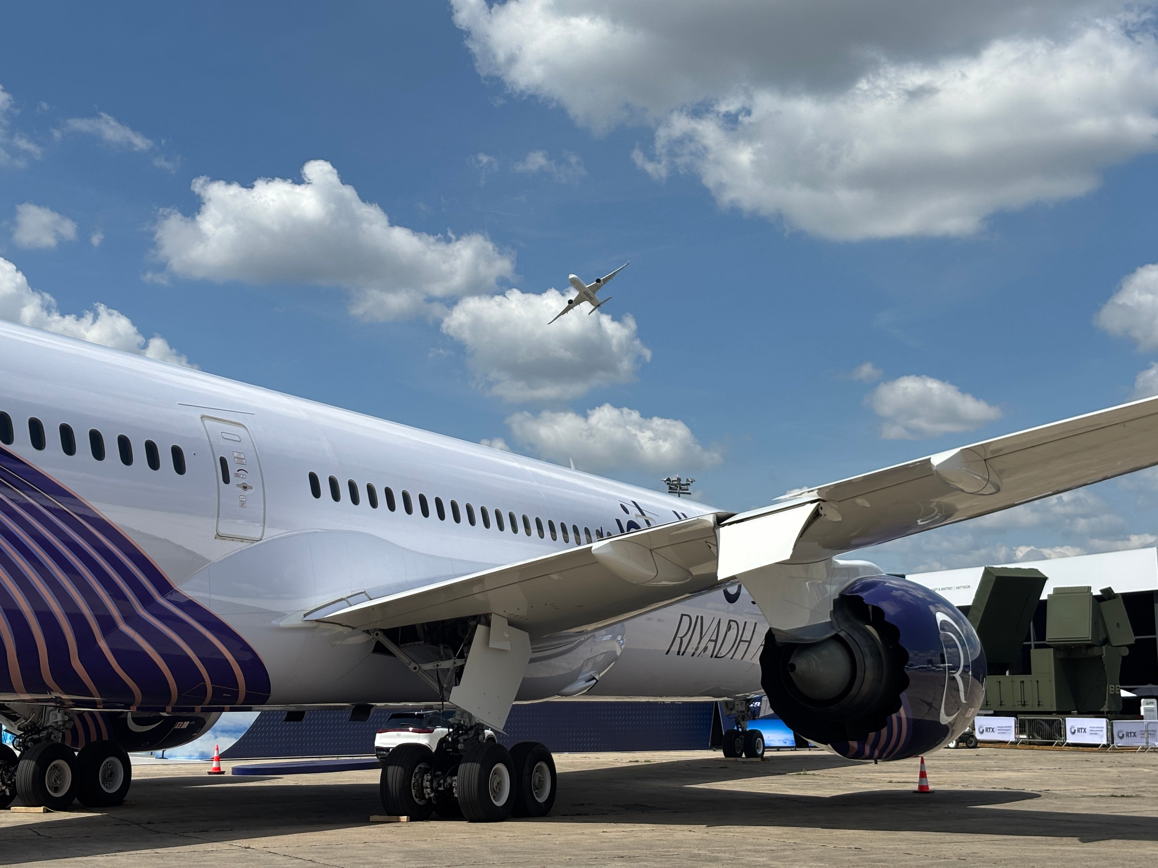 An Airbus A350-1000 flies above a Riyadh Air Boeing 787 at the Paris Air Show 2025.