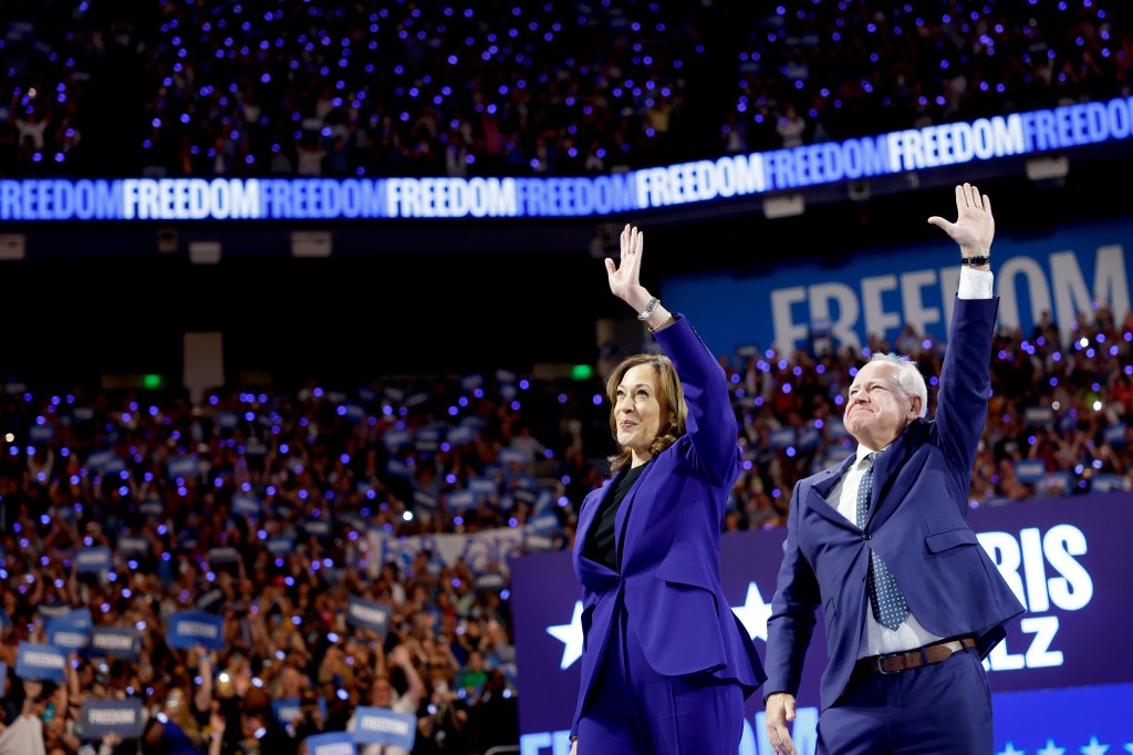 Vice President Kamala Harris and Minnesota Governor Tim Walz waving at a campaign rally.