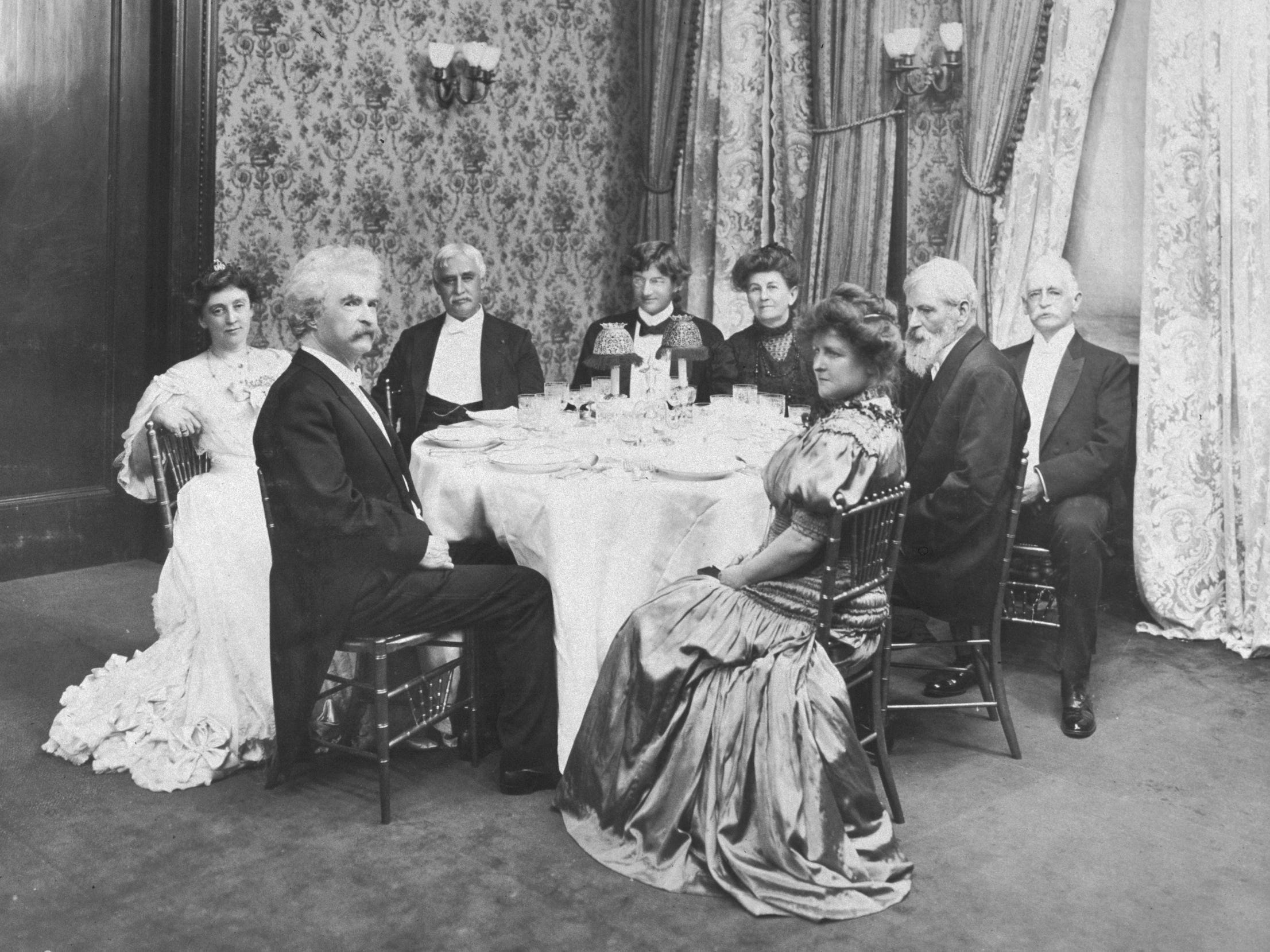 Mark Twain seated at a table with his guests celebrating his 70th birthday at the famous New York restaurant Delmonico’s in 1905.