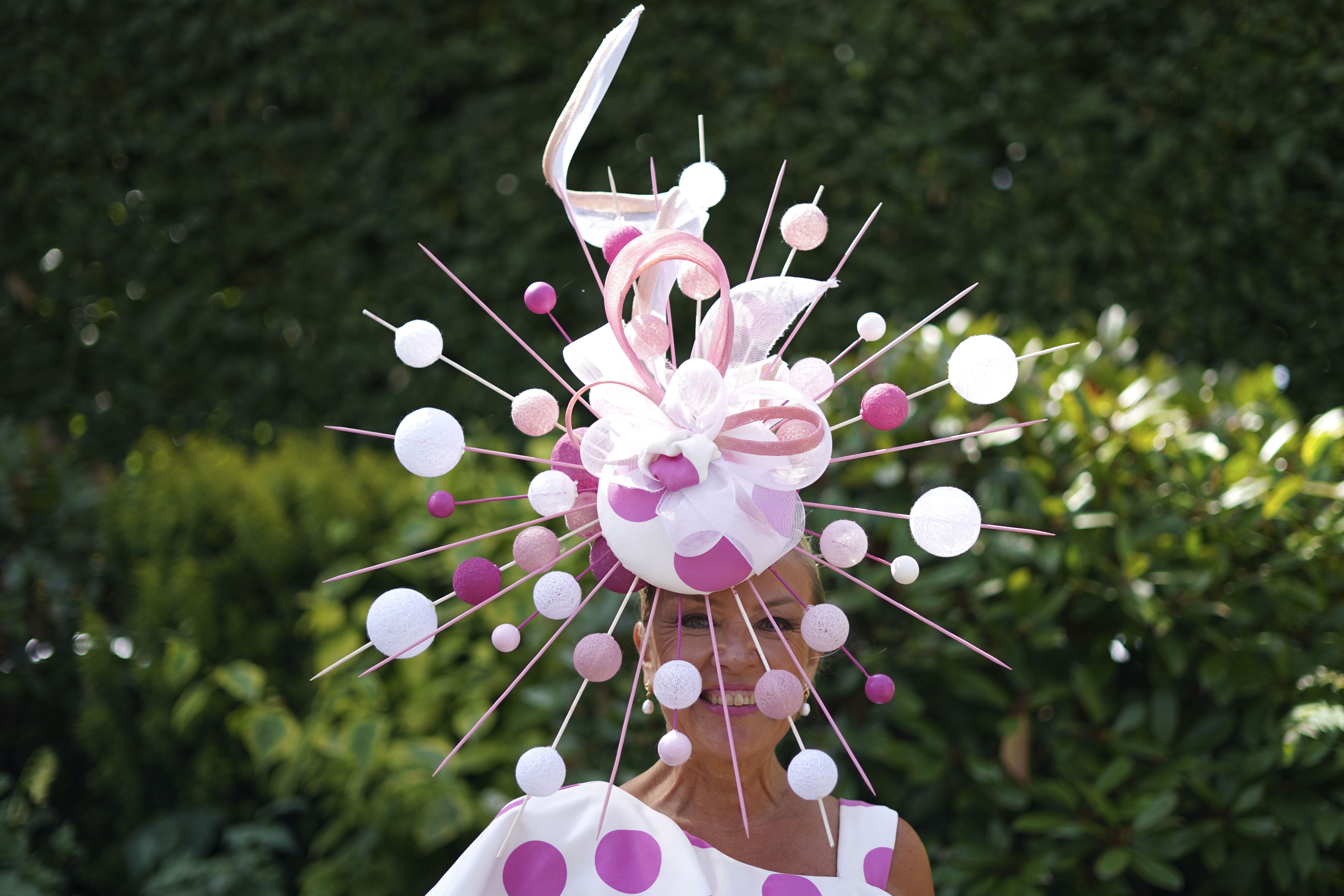 A race-goer wears an ornate hat decorated with ribbons, sticks, and balls.