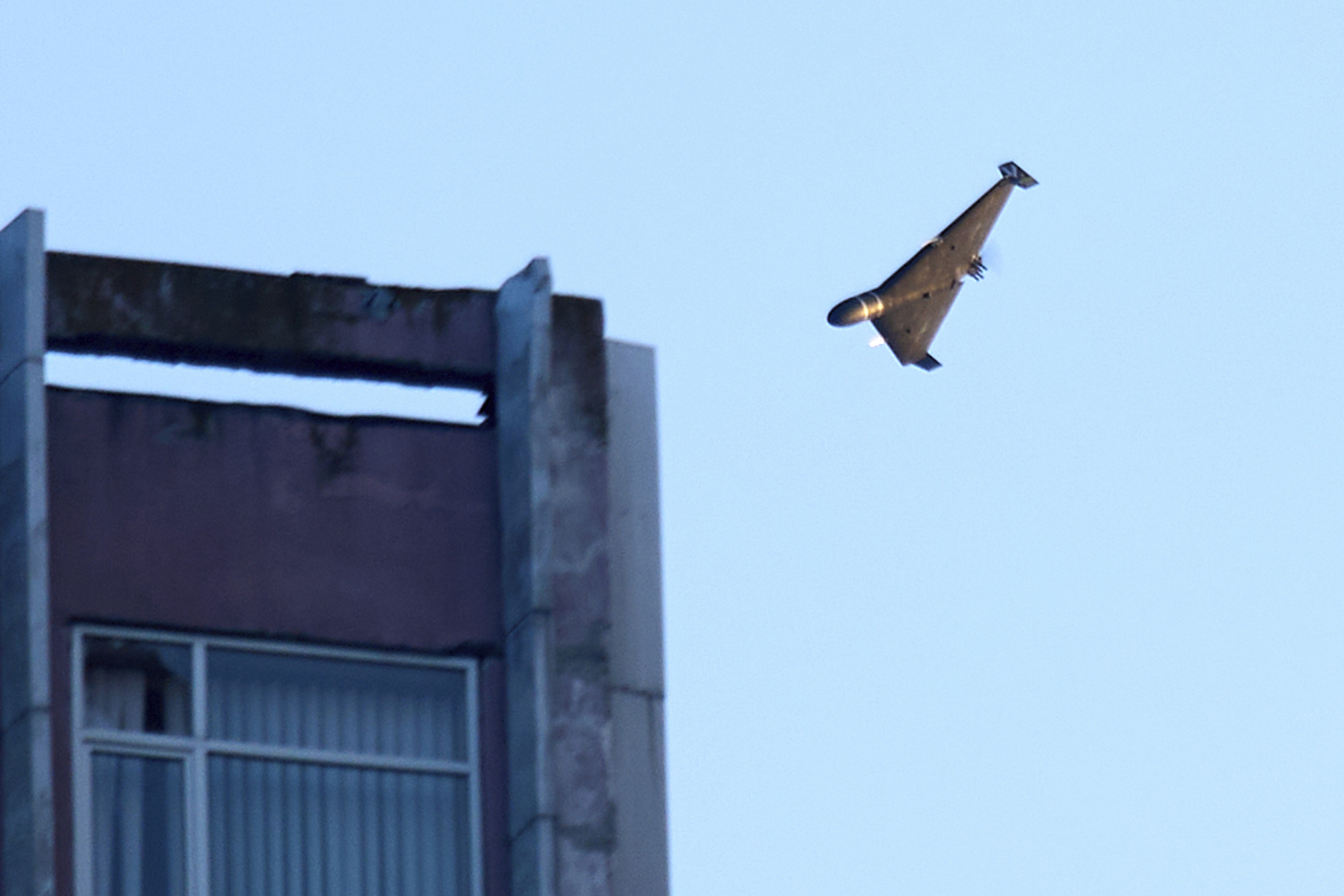 A fixed-wing drone approaches a building.