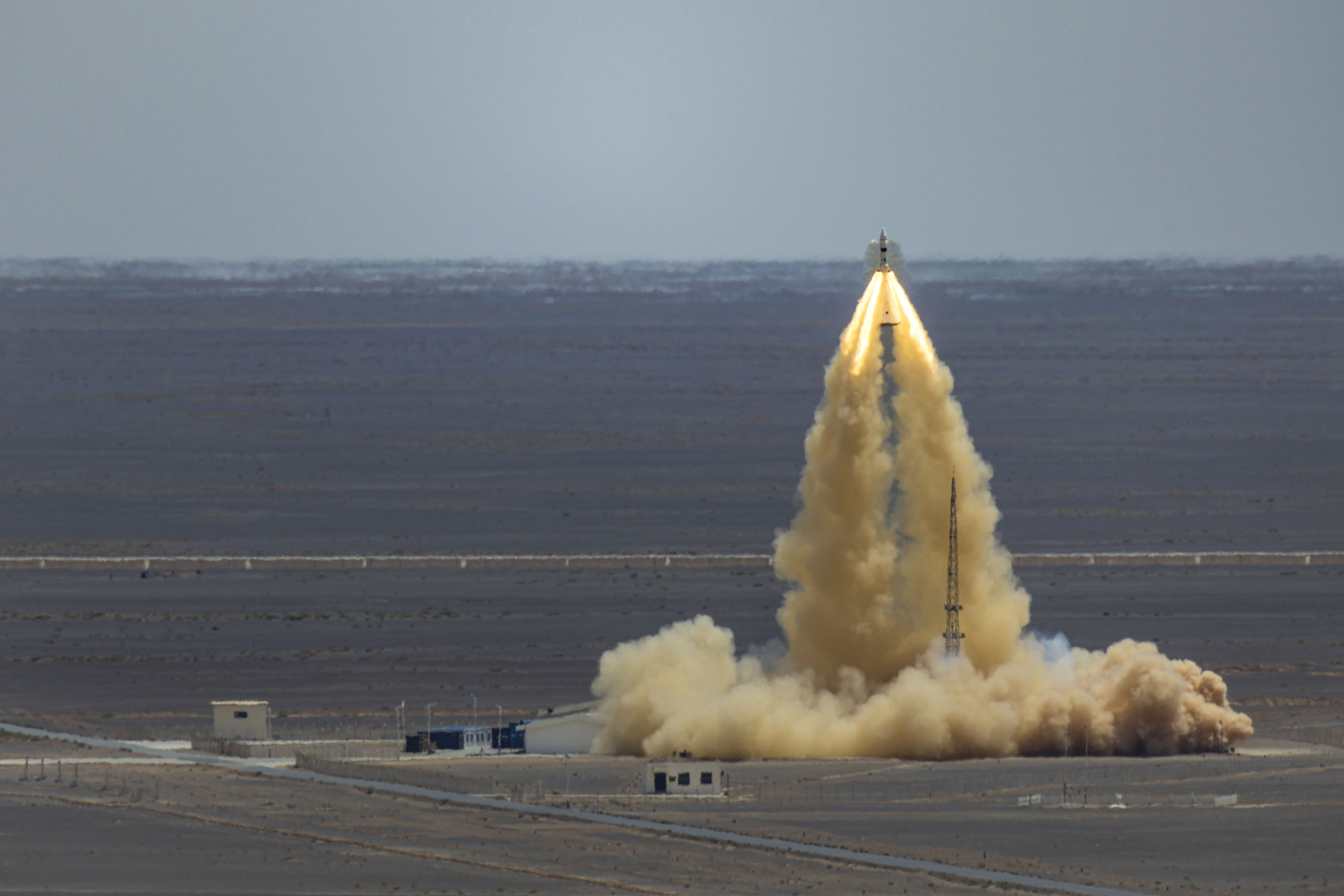 A test launch of a small spacecraft is seen in a desert setting.