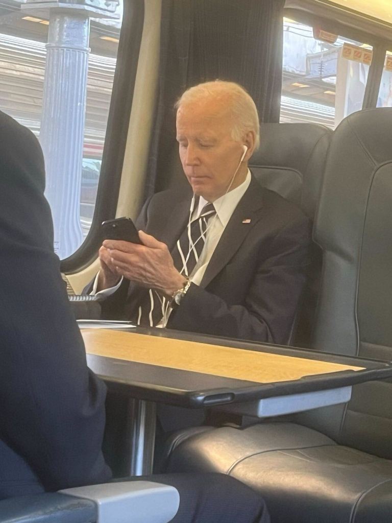 Joe Biden on a train, using his phone.