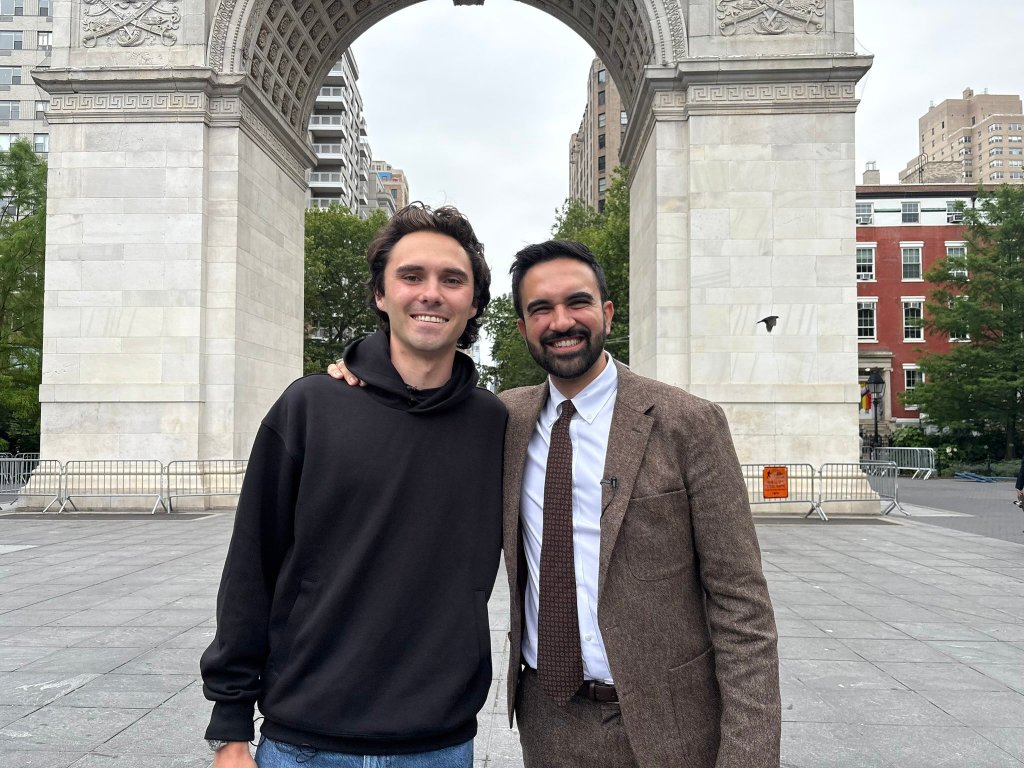 Two men posing together in front of a stone arch.