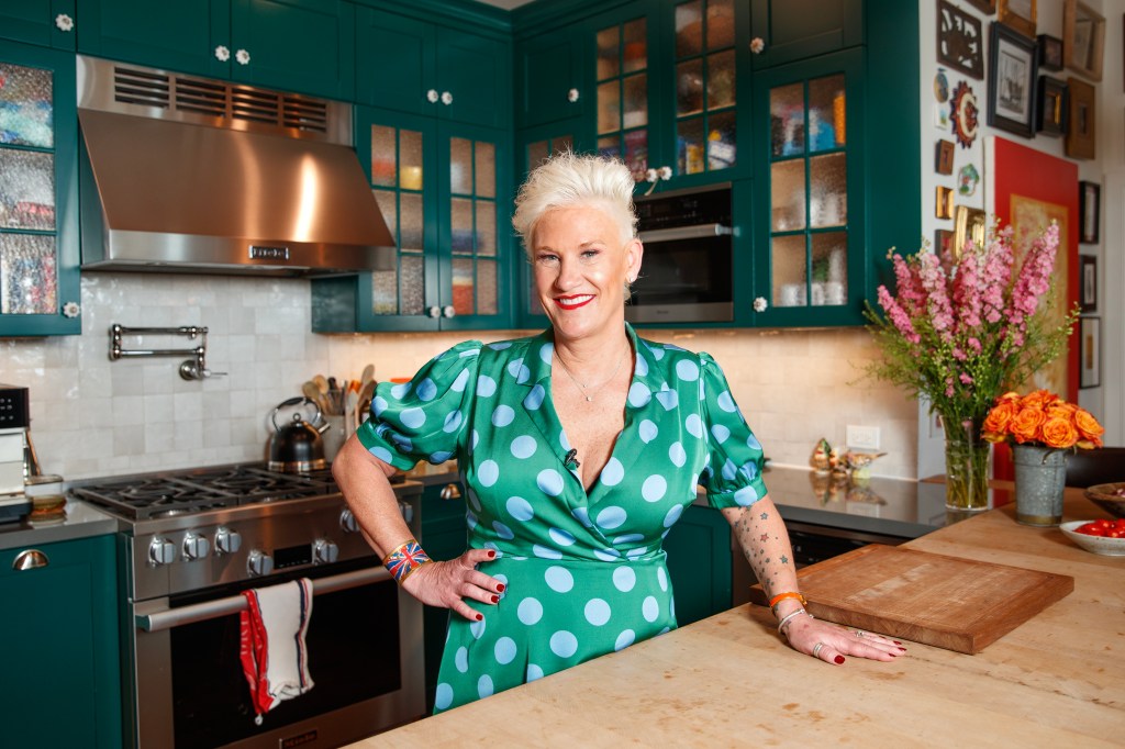 Anne Burrell with her hand on her hip in a silk polka dot dress. 