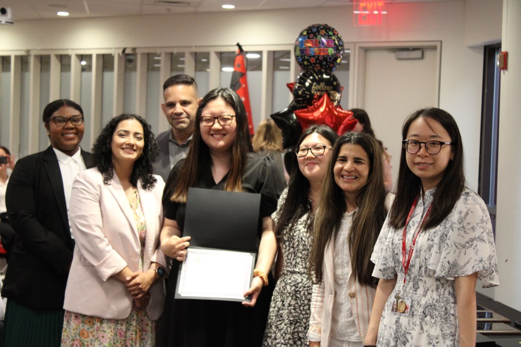Hector Diaz, at rear behind a QHHS student holding a certificate; Principal Ana De Jesus, second from right; and other assistant principals and guidance counselors