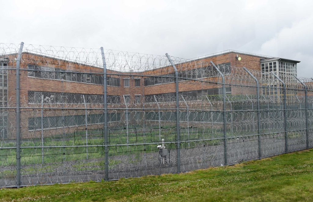 Rikers Island cell block behind a fence topped with razor wire.