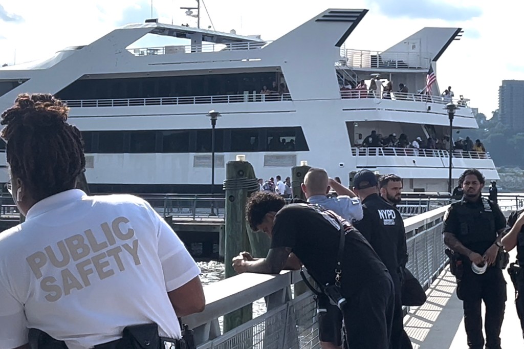 Public safety officer at a dock with a large boat and NYPD officers.
