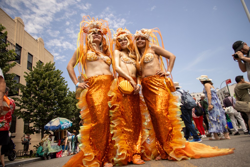 Three women in orange mermaid costumes at the Coney Island Mermaid Parade.