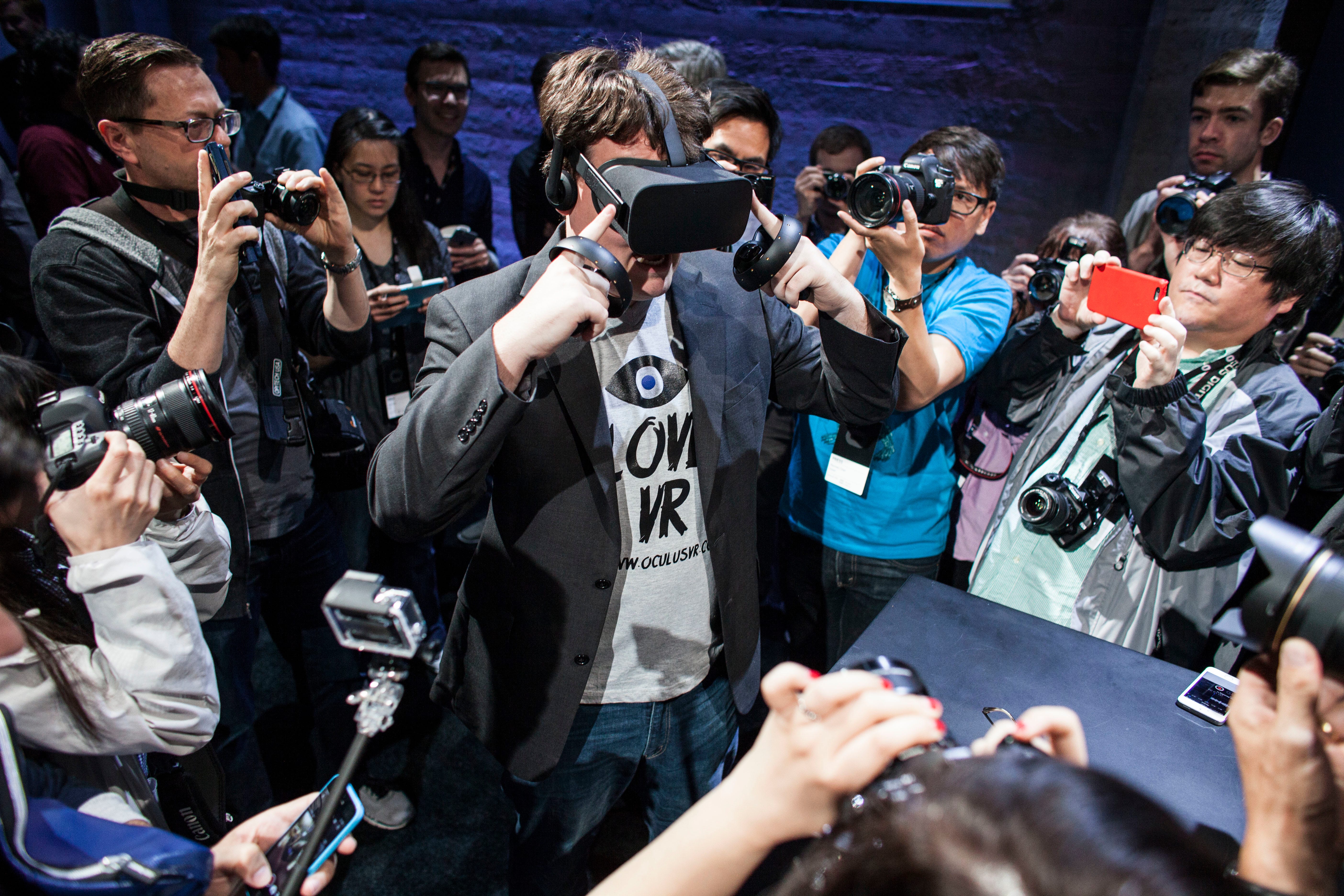 Palmer Luckey, surrounded by photographers, demonstrates the Oculus Rift headset.