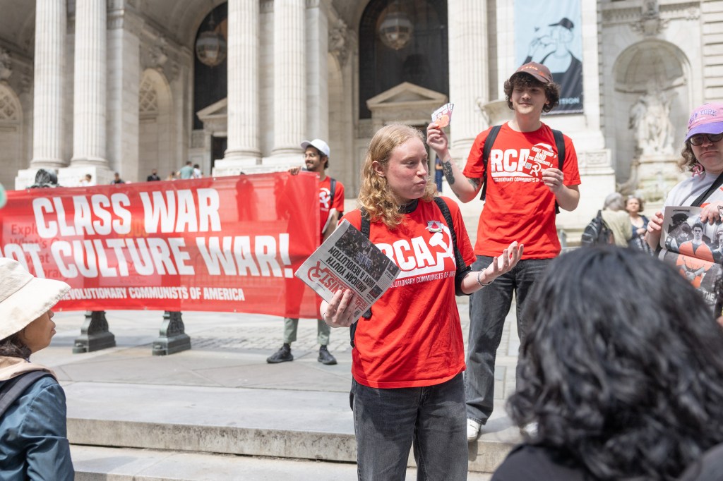 Protestors in NYC holding signs and pamphlets at an Earth Day demonstration against Trump's policies.