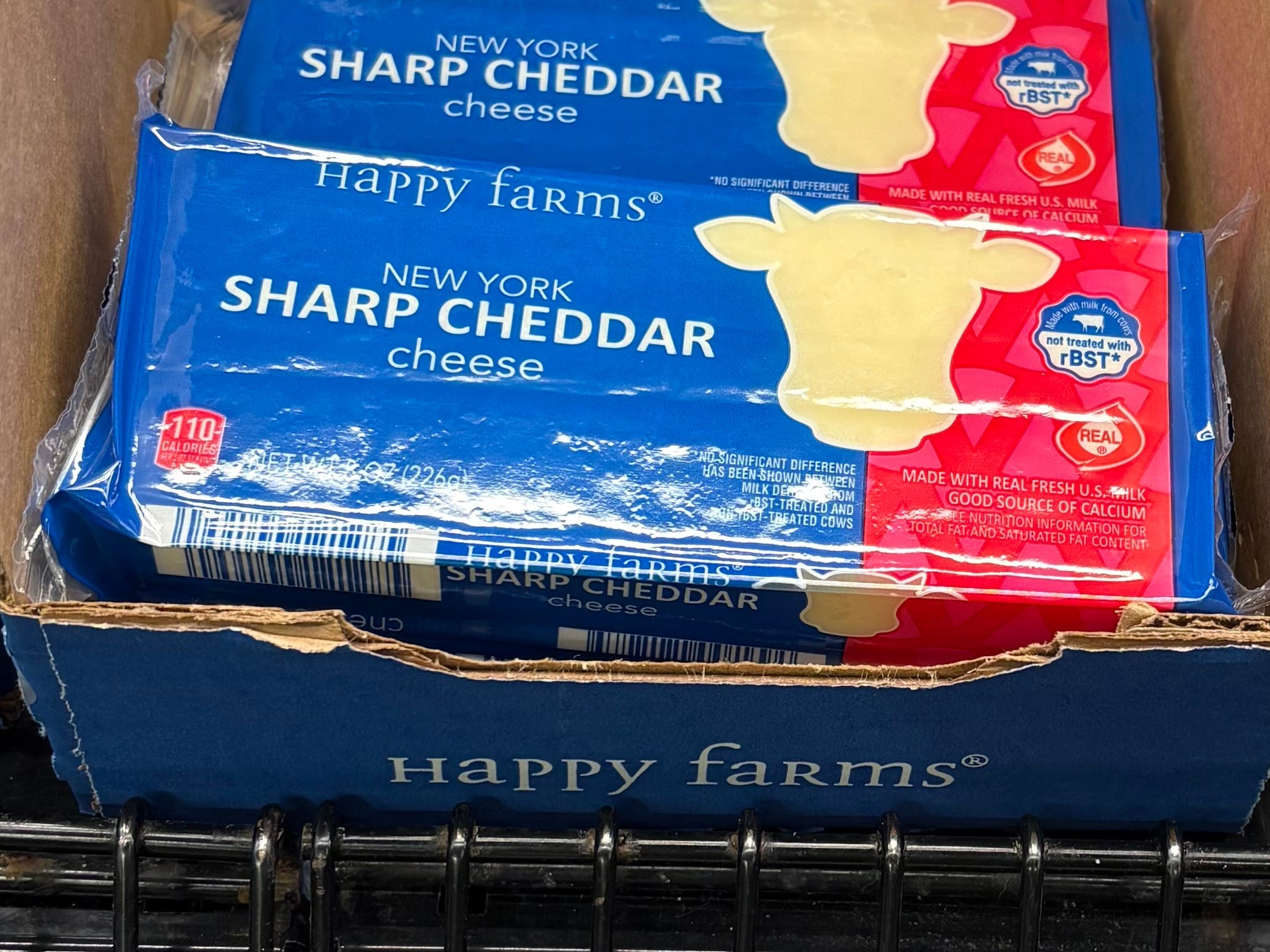 A display of Happy Farms New York sharp cheddar cheese at Aldi.