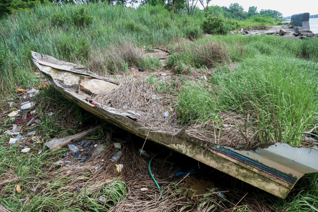 An abandoned boat sits on the shore of Westchester Creek.