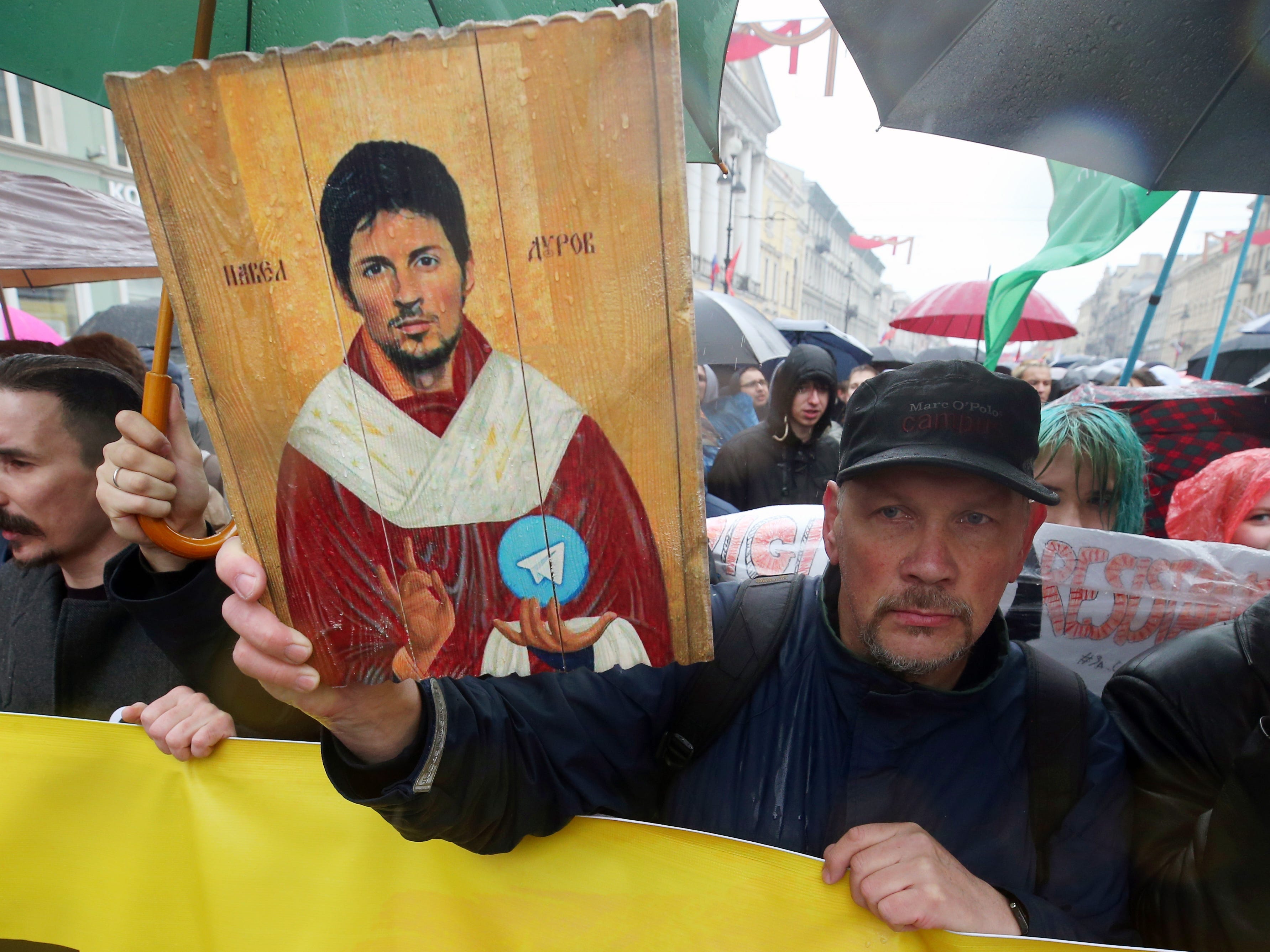 Protestors hold sign of Pavel Durov painted in the manner of a Catholic Saint