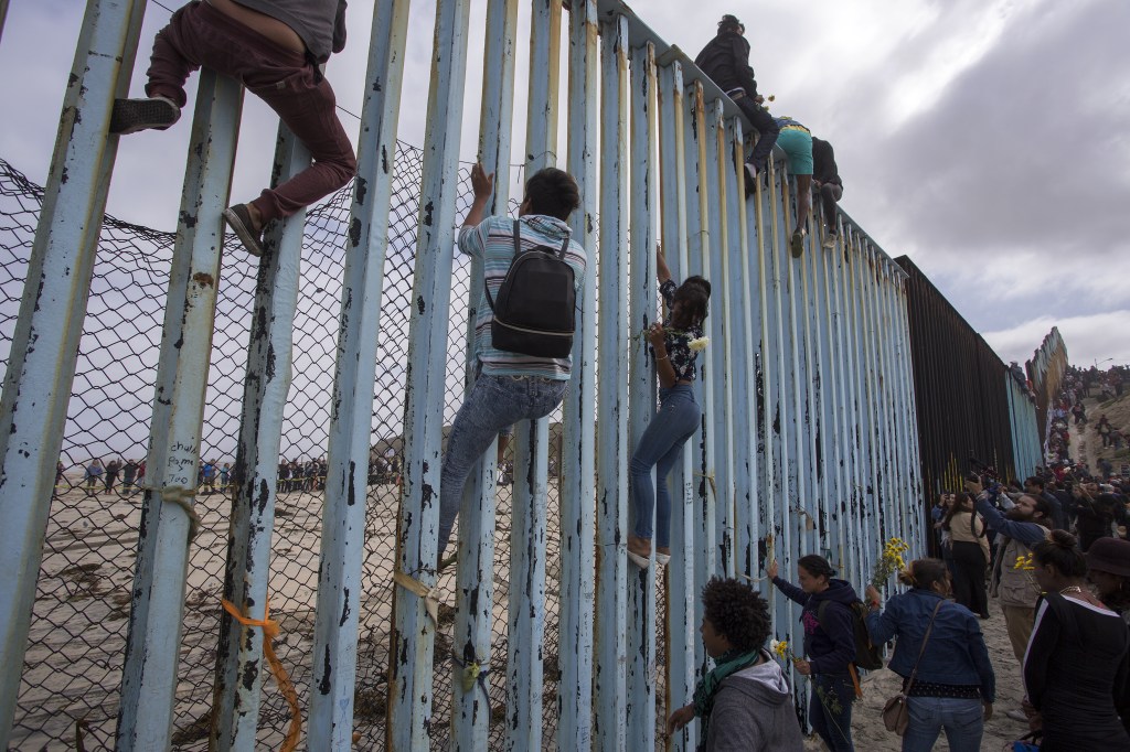 Migrants climbing border fence to seek asylum.