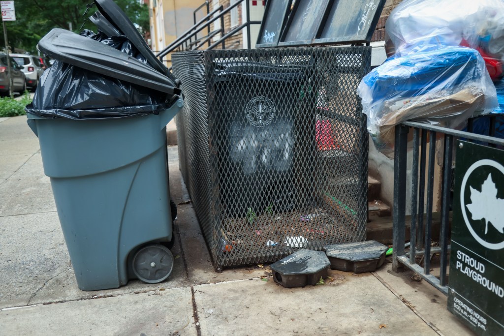 Trash cans and rat traps on a city sidewalk.