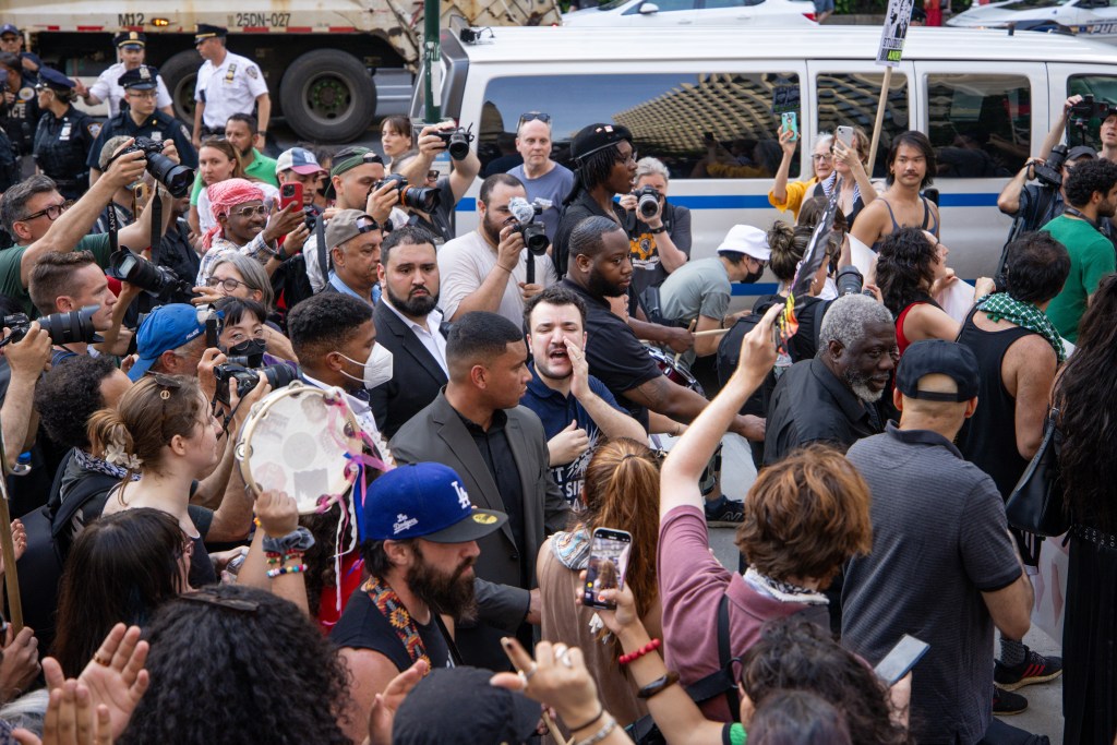 A large crowd of people surrounding a person shouting.