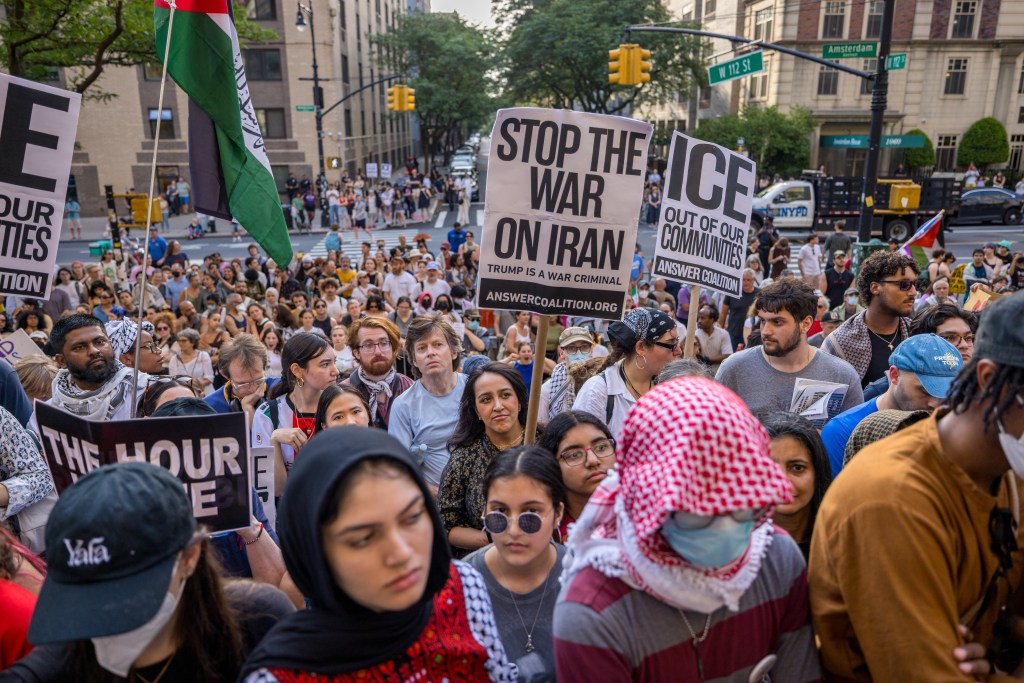 Protestors holding signs against war and ICE.