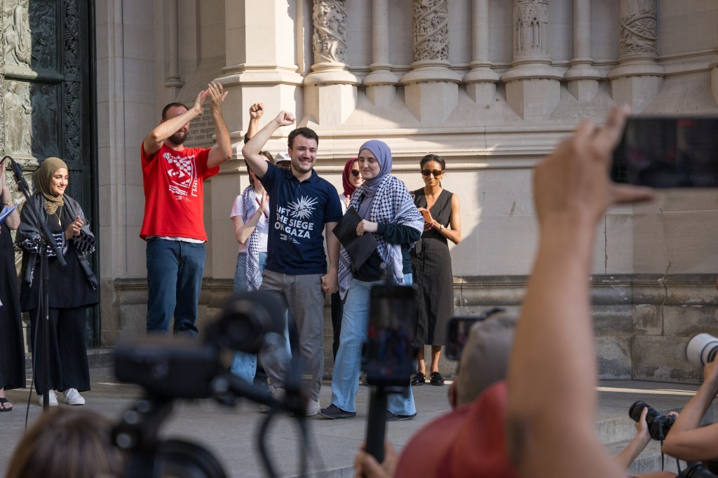 Protestors holding signs and raising their fists in front of a building.