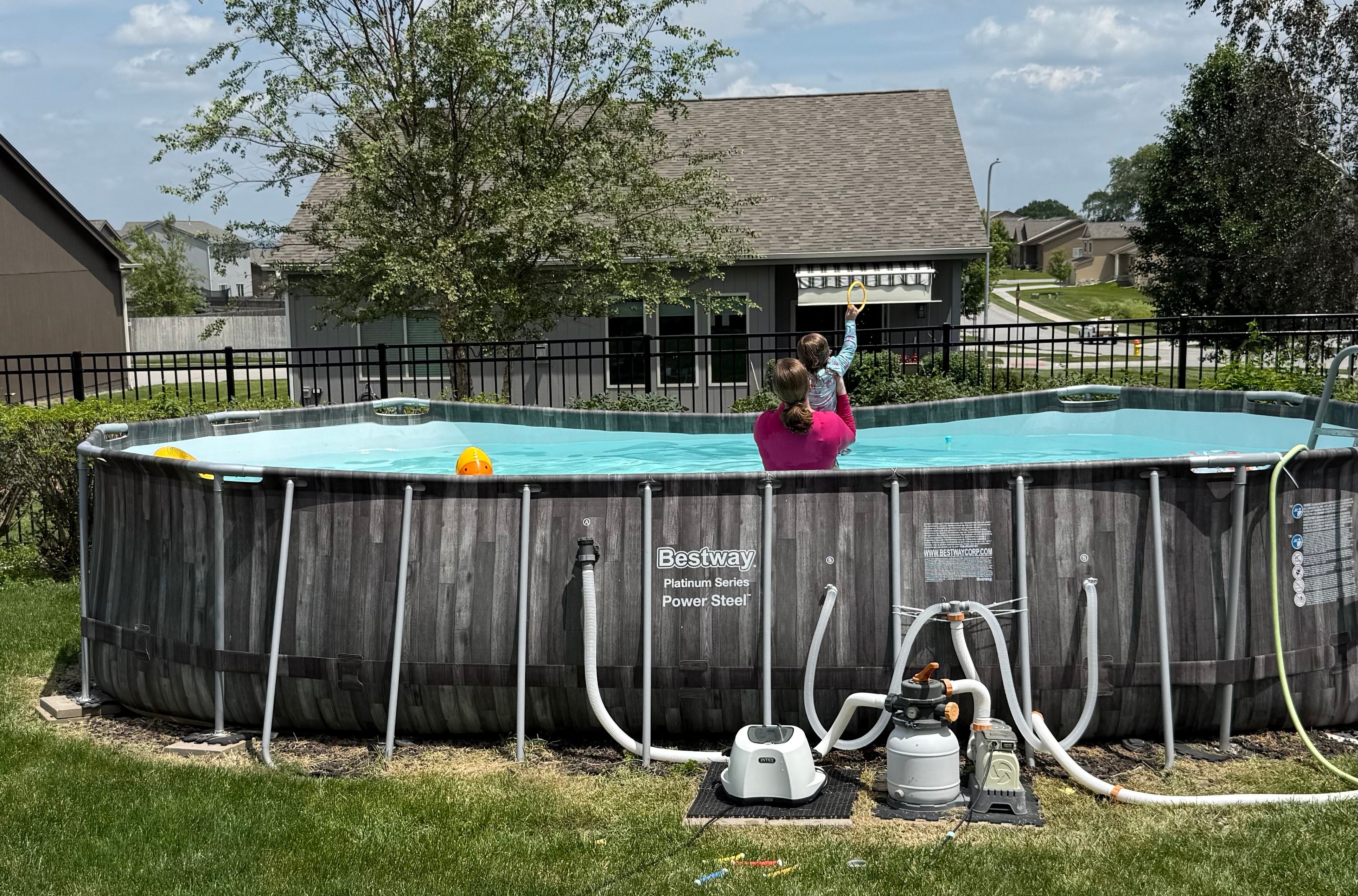 A woman plays with a young boy in an above ground pool.