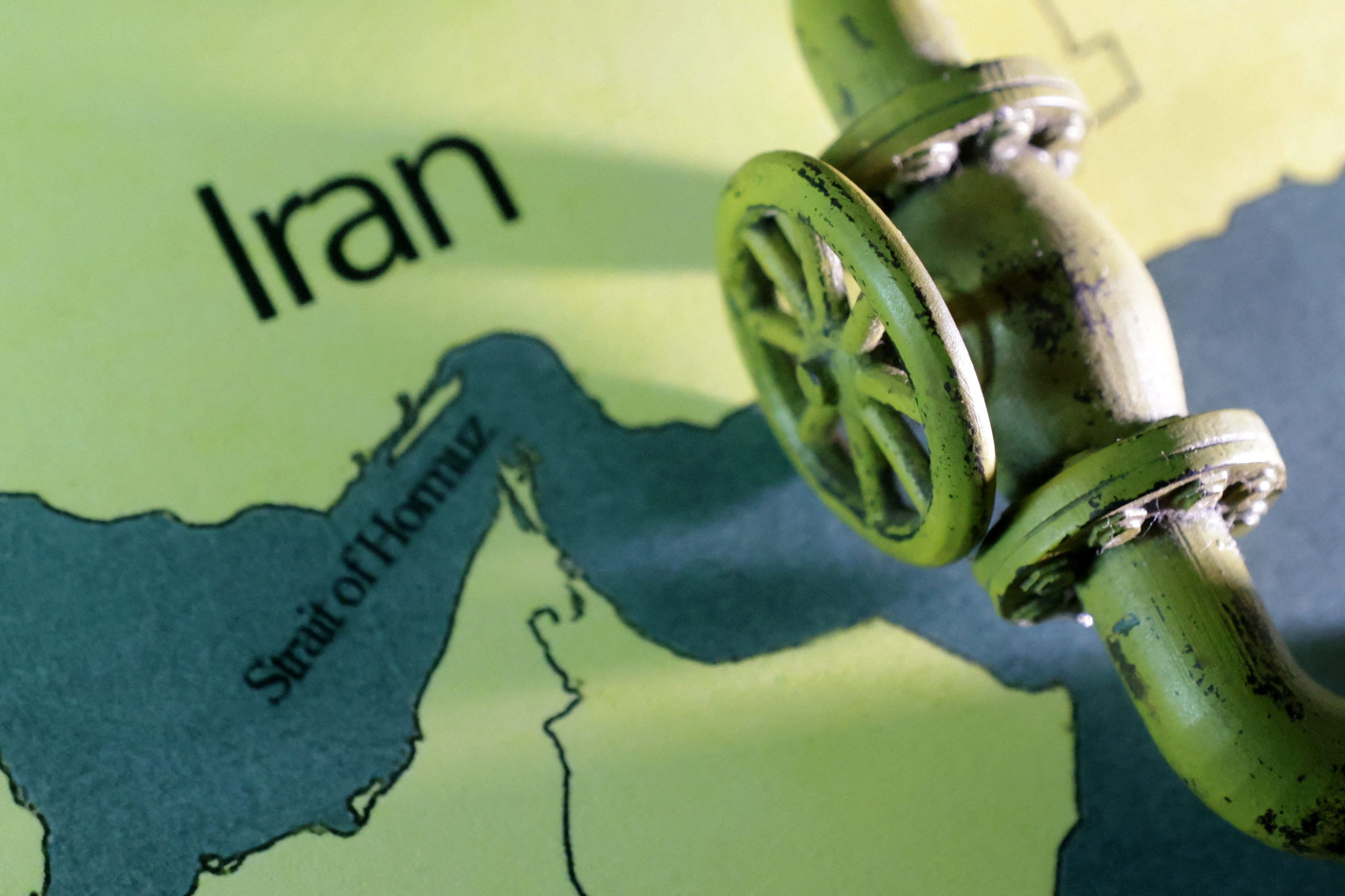 A map showing the Strait of Hormuz and Iran is seen behind a 3D printed oil pipeline.