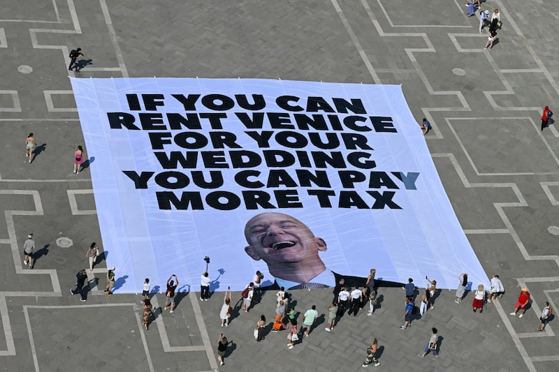 Activists of international environmental group Greenpeace deploy a giant banner displaying a picture of Jeff Bezos and reading "If you can rent Venice for your wedding you can pay more tax" at St Mark square in Venice on June 23, 2025. Venice will host the wedding of Amazon Founder and CEO Jeff Bezos and journalist Lauren Sanchez before the end of the month with more than 200 guests expected to attend. (Photo by Stefano Rellandini / AFP) (Photo by STEFANO RELLANDINI/AFP via Getty Images)