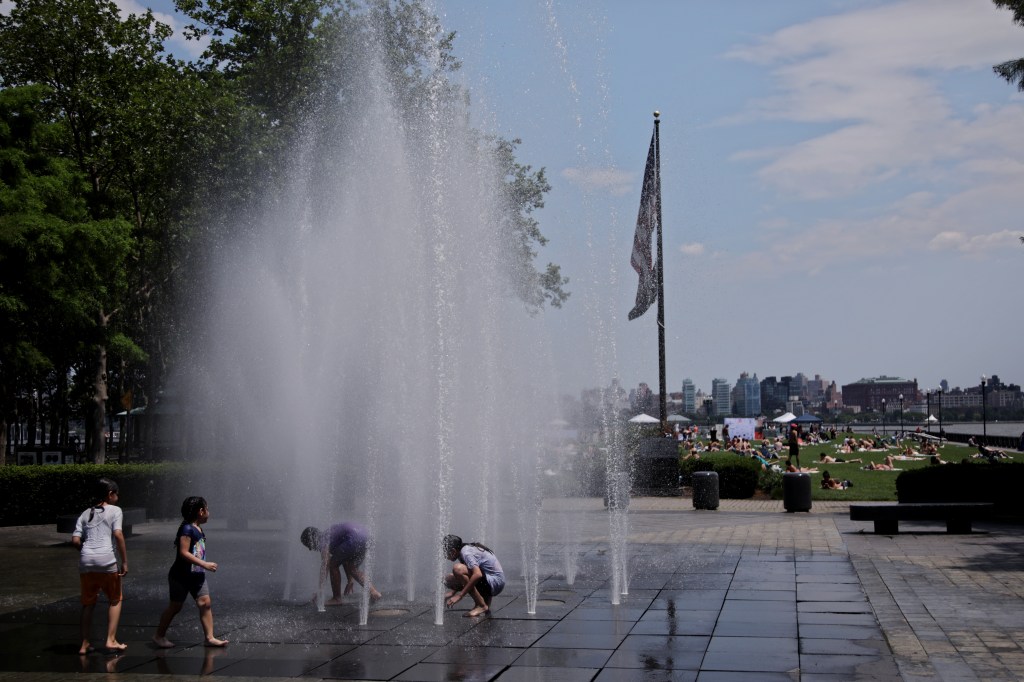 Children playing in a water fountain on a hot day.
