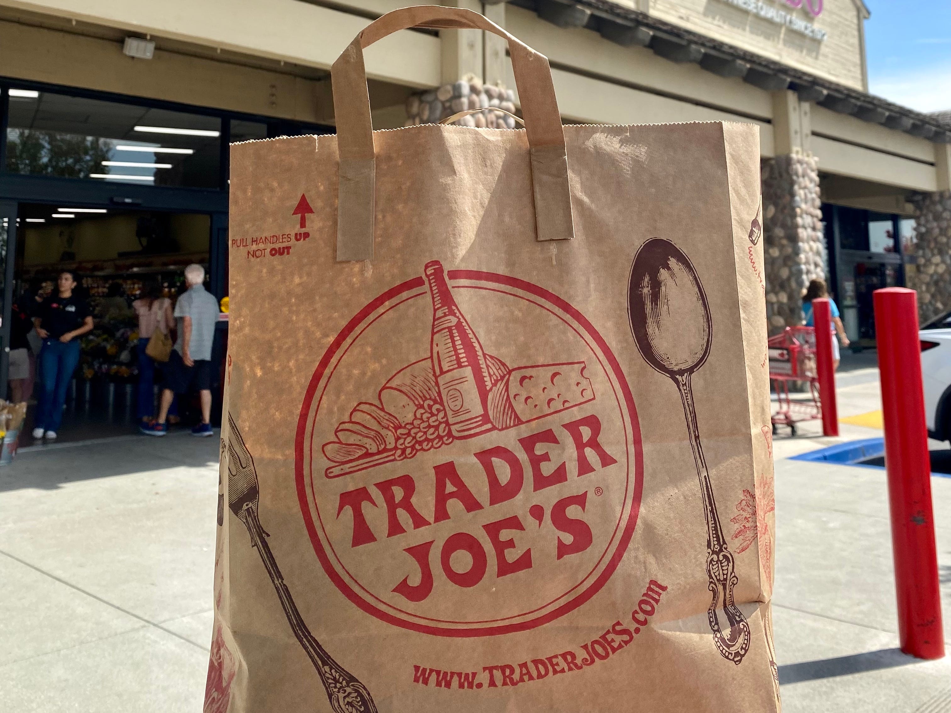 Trader Joe's bag in front of Trader Joe's grocery store sign.