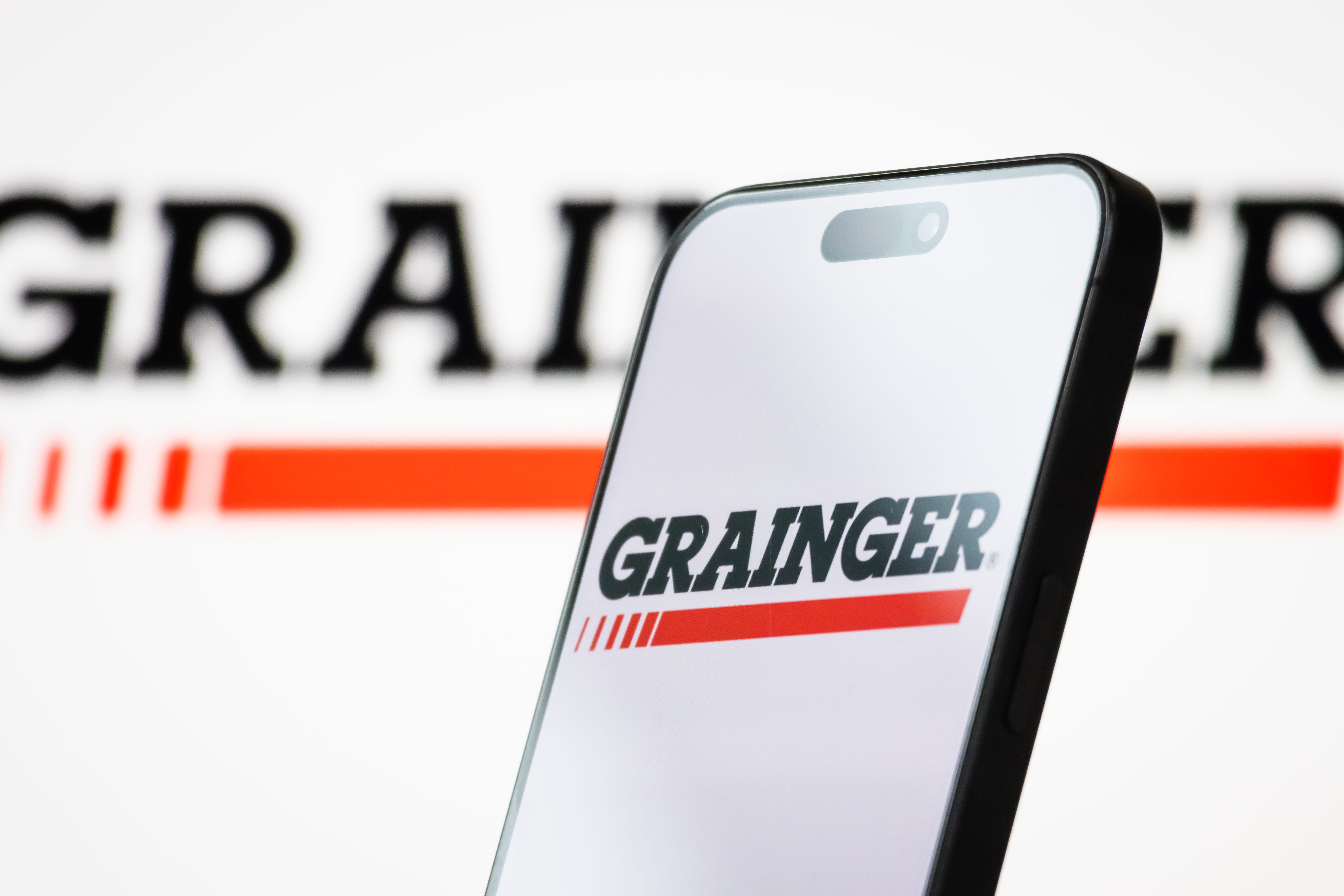 The logo of W.W. Grainger, Inc. is displayed on a smartphone screen, with the company's red and black branding visible in the background.