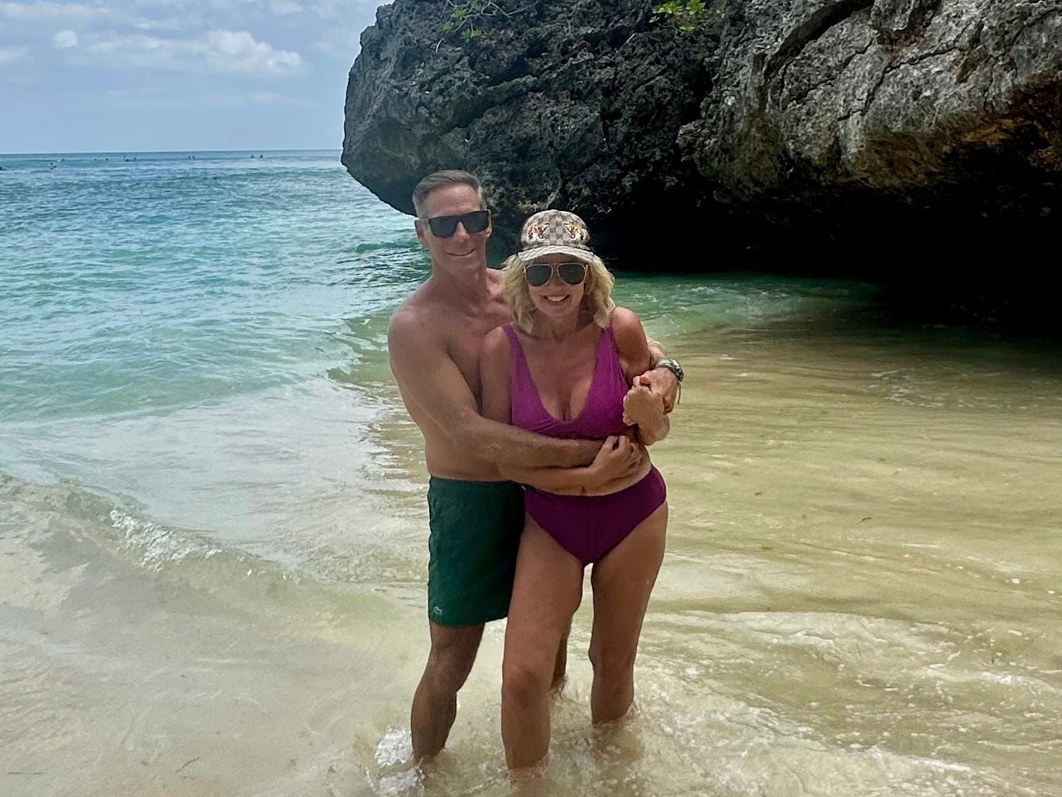 The author and her husband standing in the water on a beach.