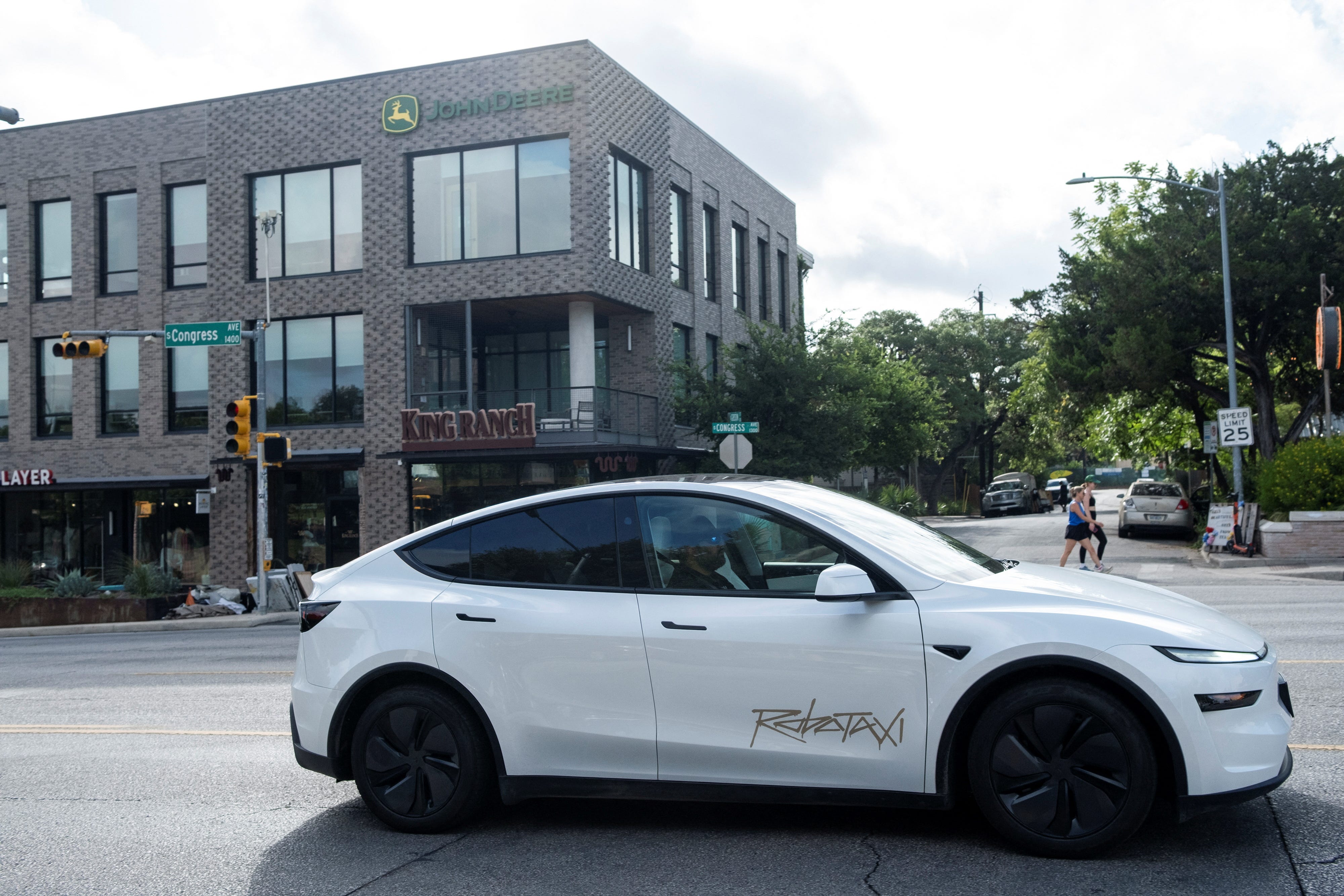 A Tesla robotaxi drives down a street in Austin