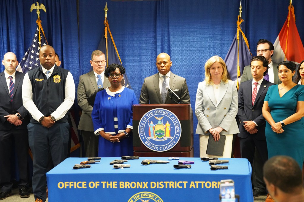 Press conference with Mayor Eric Adams and Bronx District Attorney Darcel Clark about city crimes; several confiscated guns are displayed on a table.