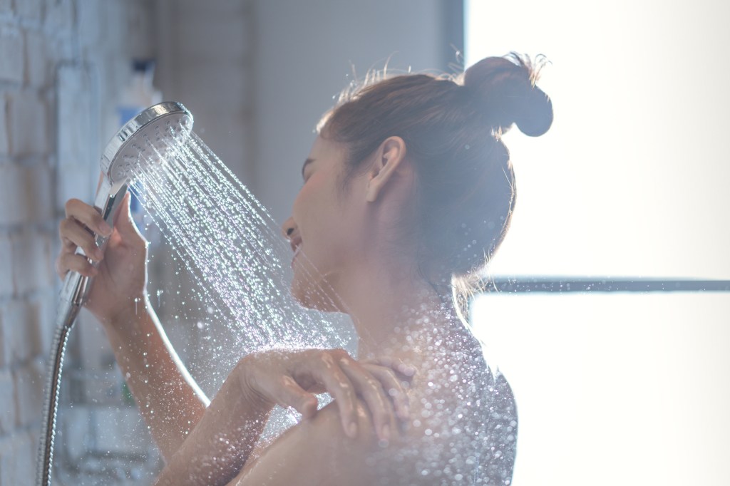 Woman showering and washing her shoulders.