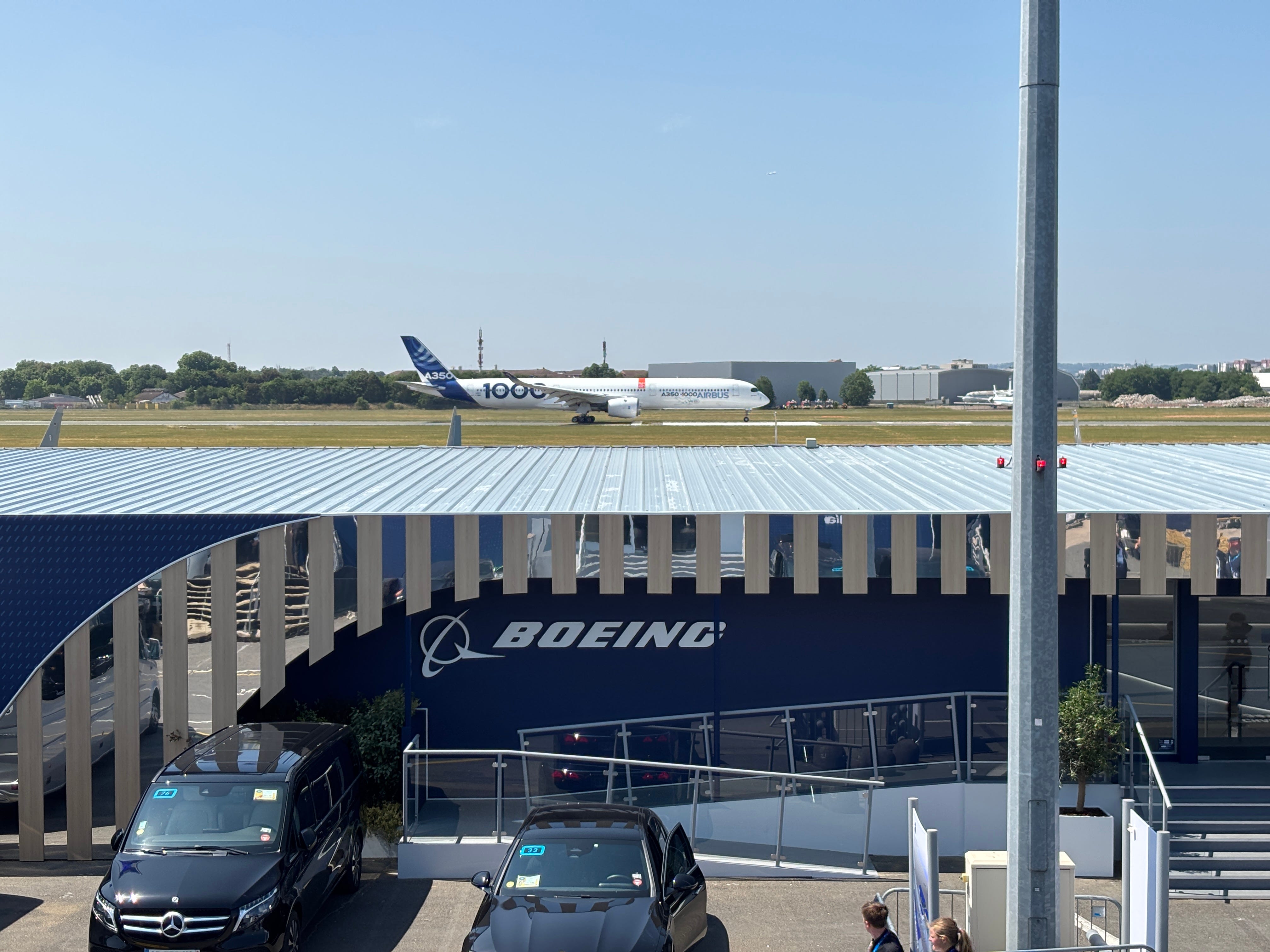 An Airbus A350-1000 takes off on the runway at Le Bourget Airport, behind a Boeing Chalet at the 2025 Paris Air Show
