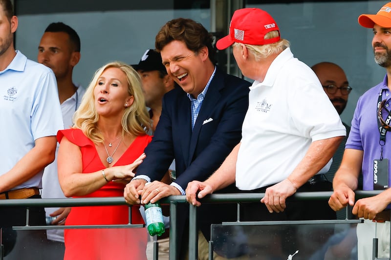 President Donald Trump, Tucker Carlson, and Marjorie Taylor Greene share a laugh during a 2022 LIV Golf tournament. The two conservatives continued backing Trump even while he was in political exile after the Jan. 6, 2021, riots at the U.S. Capitol.
