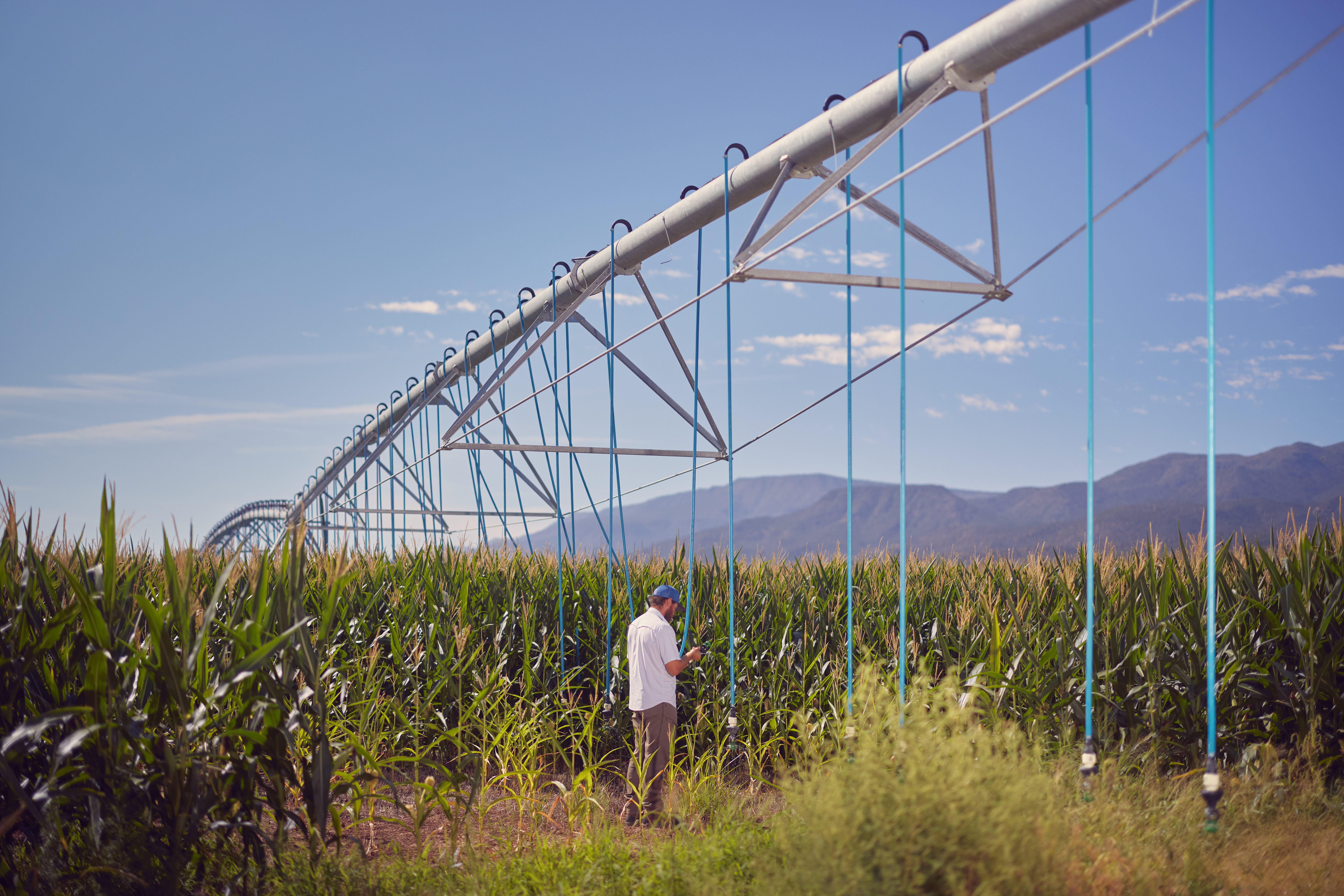 A man standing beside a mechanized irrigation system.
