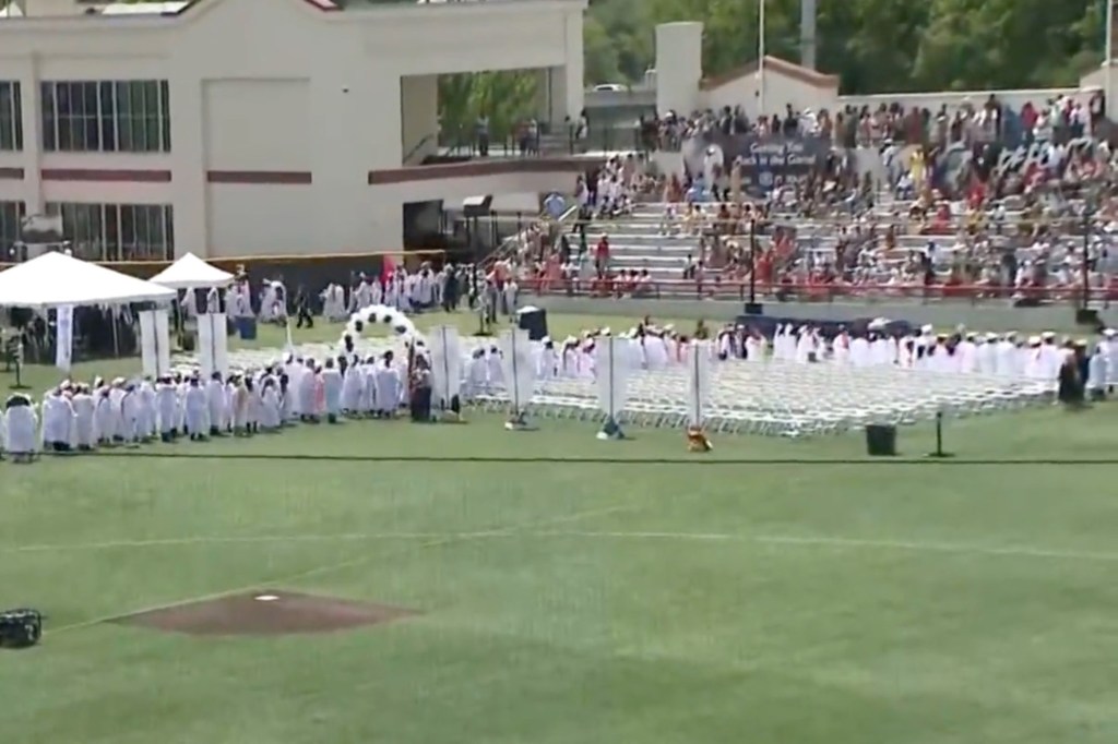 Graduates in gowns at an outdoor graduation ceremony.