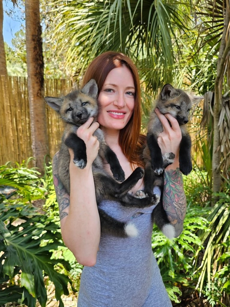 Woman holding two fox kits.