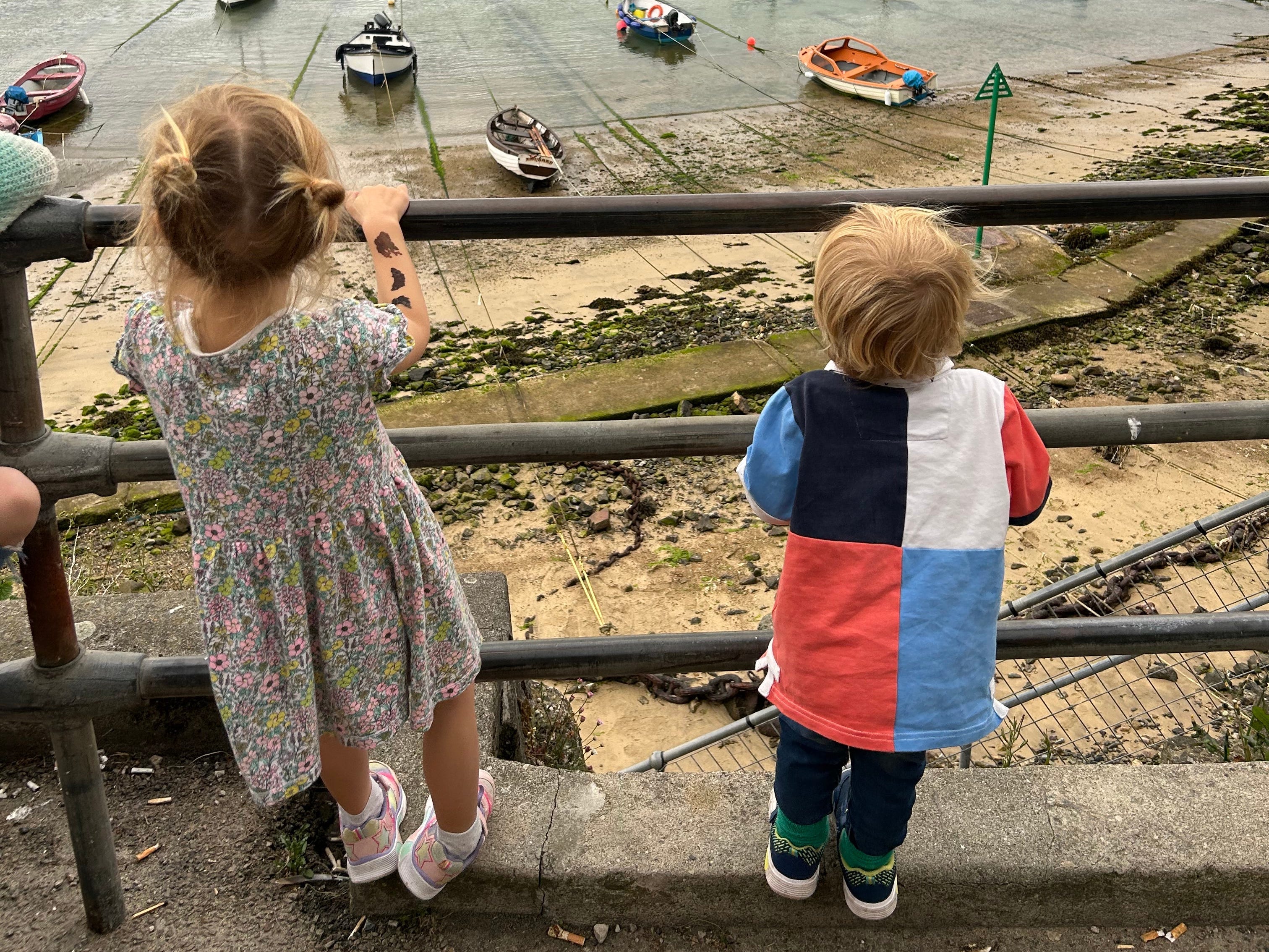 The author's two kids looking over a guardrail at boats in a bay.