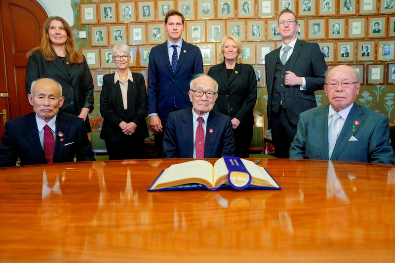 Representatives of last year’s winner of the Nobel Peace Prize, Toshiyuki Mimaki, Terumi Tanaka, and Shigemitsu Tanaka. Behind them is the Norwegian Nobel Committee. From left, they are: Gry Larsen, Anne Enger, Jorgen Watne Frydnes, Kristin Clemet, and Asle Toje.