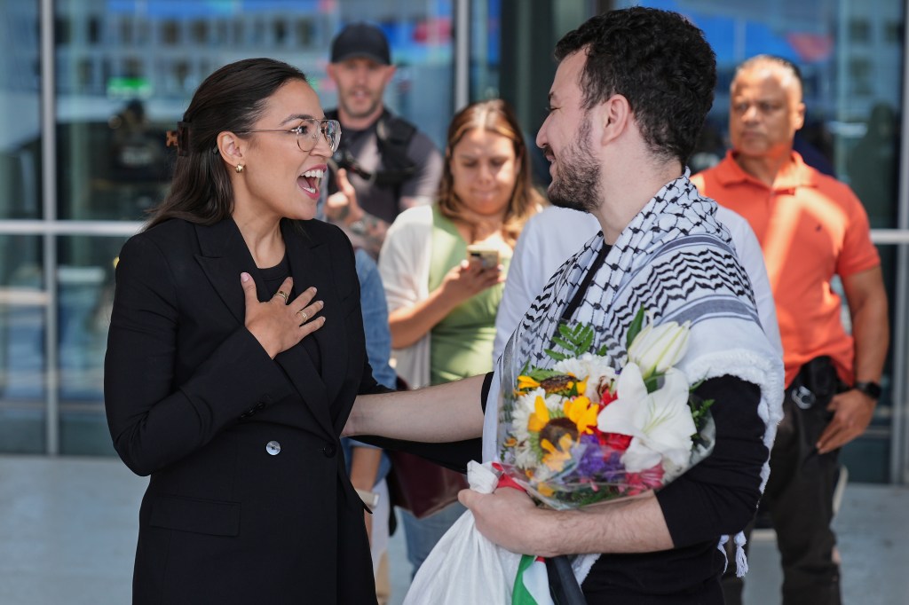Rep. Alexandria Ocasio-Cortez speaks with Mahmoud Khalil, who presents her with flowers.