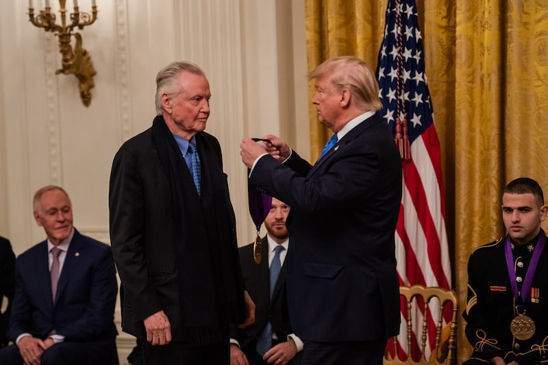 Jon Voight and Donald Trump in front of a gold curtain.