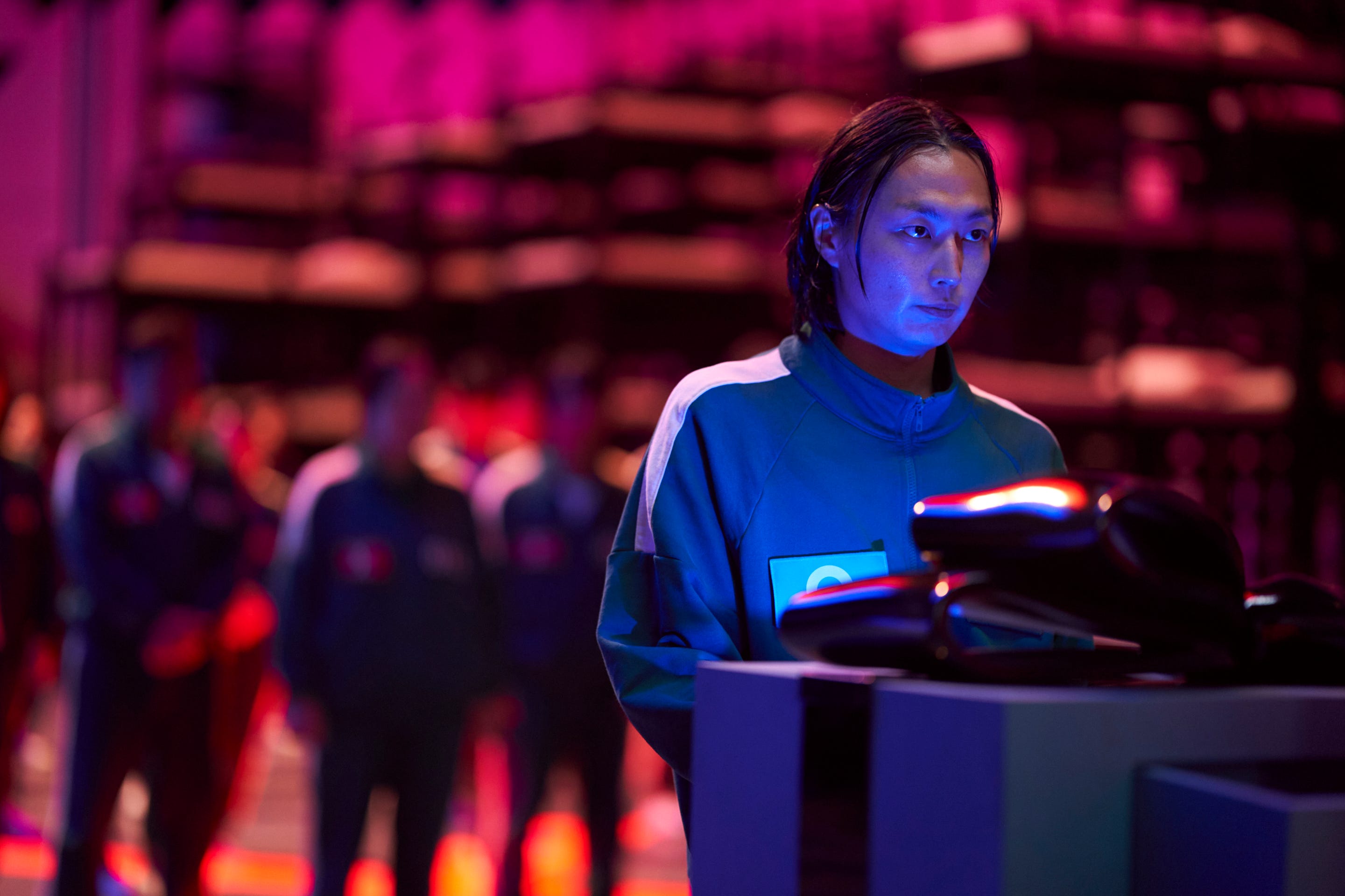 A still of "Squid Game" season two showing Roh Jae-won wearing a green tracksuit and pressing a button.