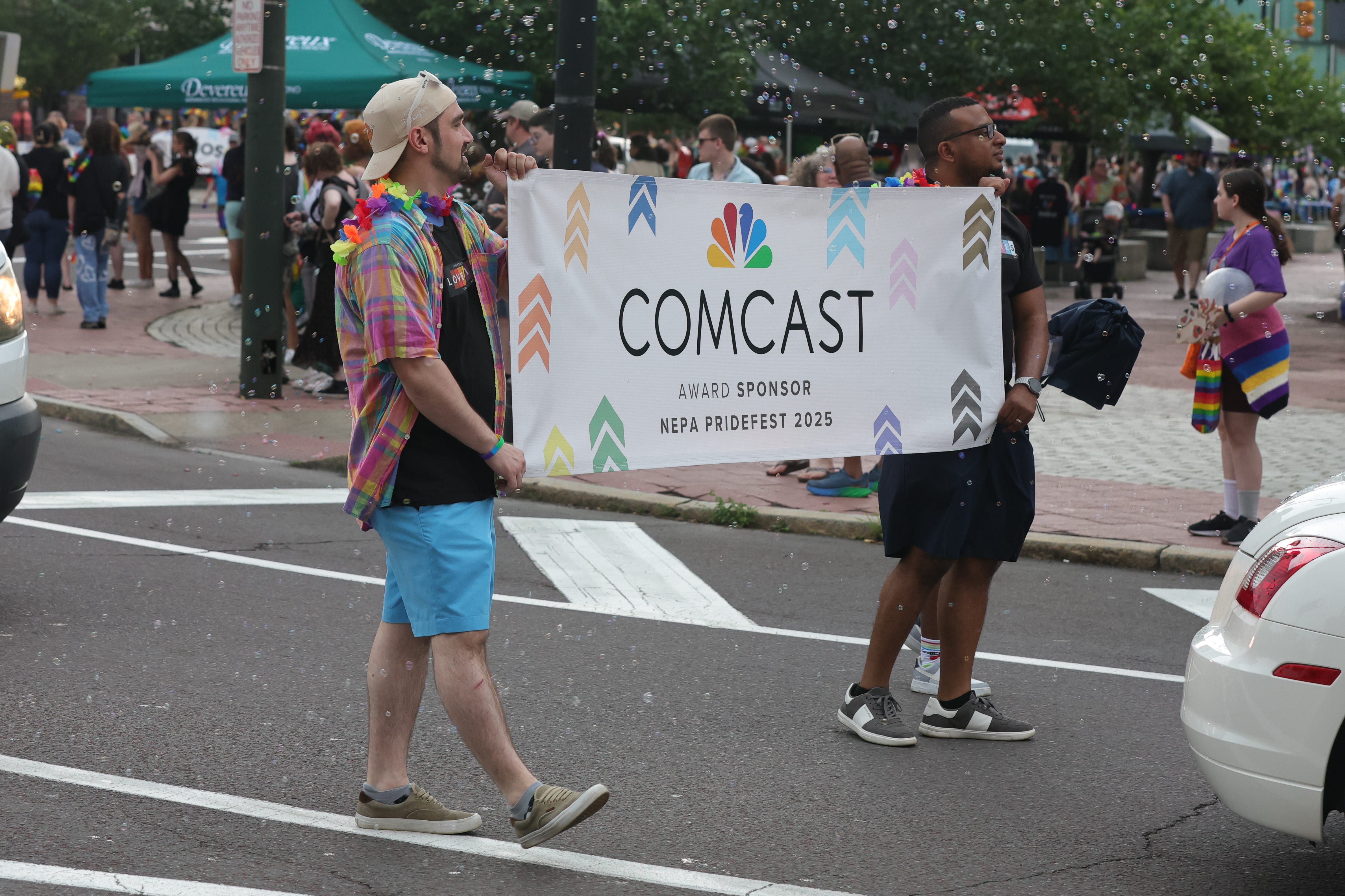 People carry a banner for Comcast in the NEPA PrideFest parade on Wilkes-Barre's Public Square. NEPA PrideFest, organized by the Rainbow Alliance, is a vibrant annual celebration in Northeastern Pennsylvania that encompasses a diverse range of activities, typically held in late June.